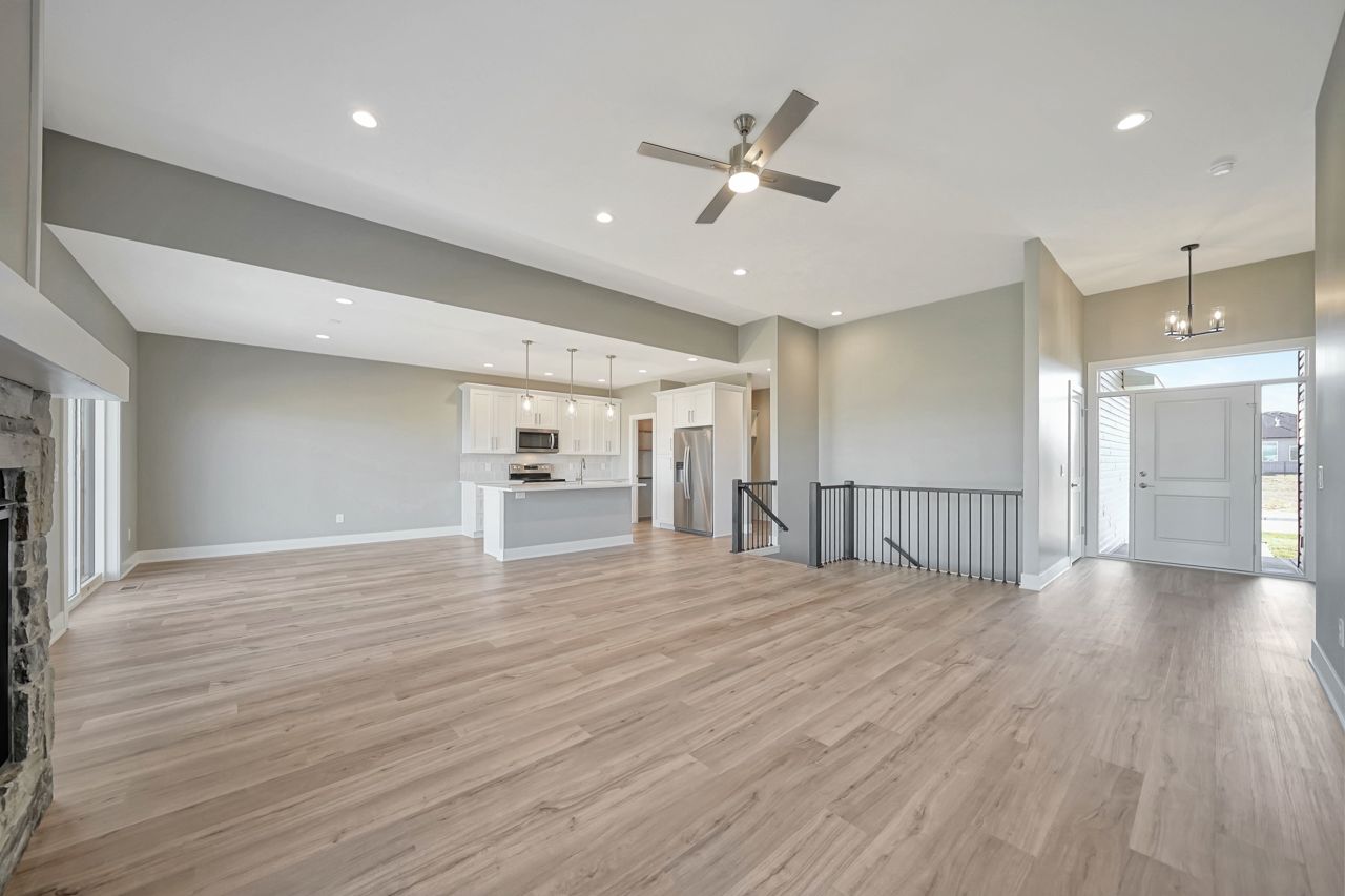 A large empty living room with hardwood floors and a ceiling fan.