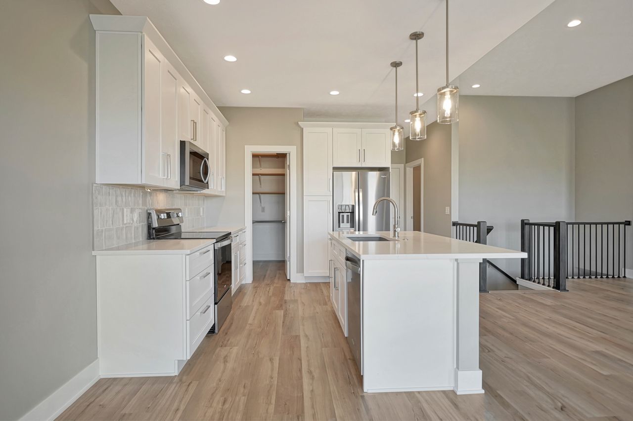 A kitchen with white cabinets , stainless steel appliances , and a large island.