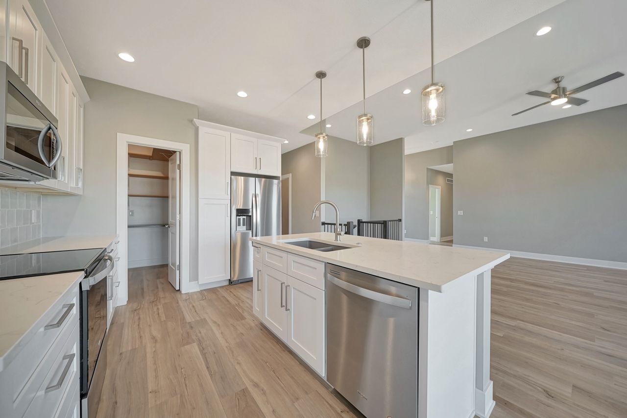 A kitchen with white cabinets , stainless steel appliances , and a large island.