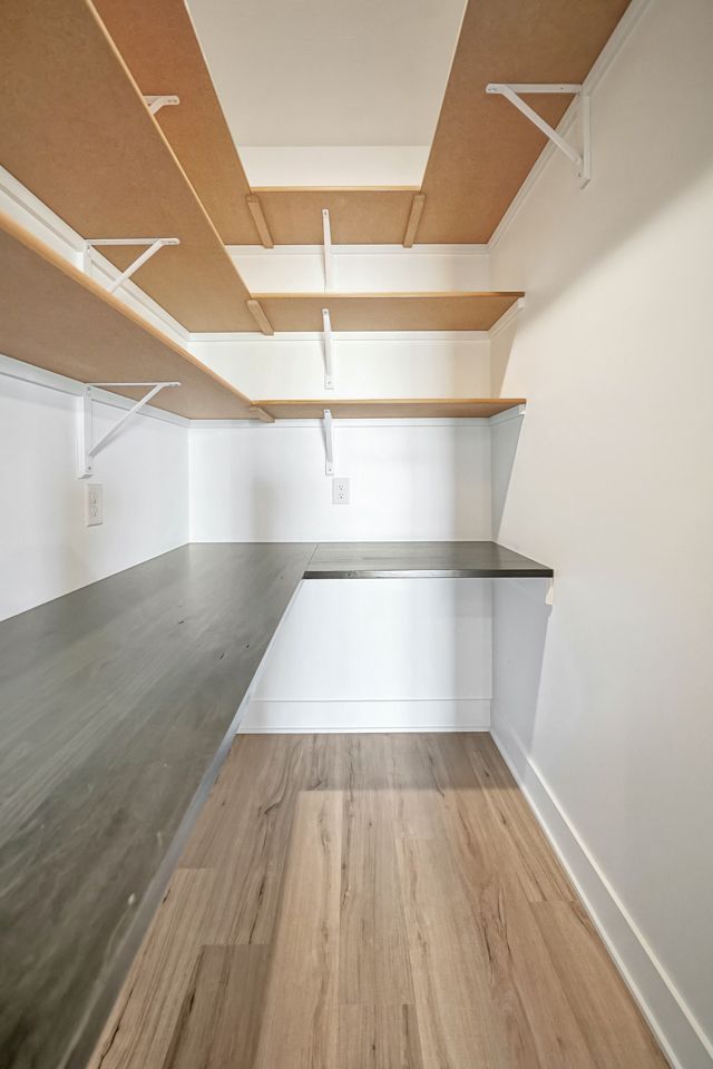 A narrow room with shelves and a wooden floor.