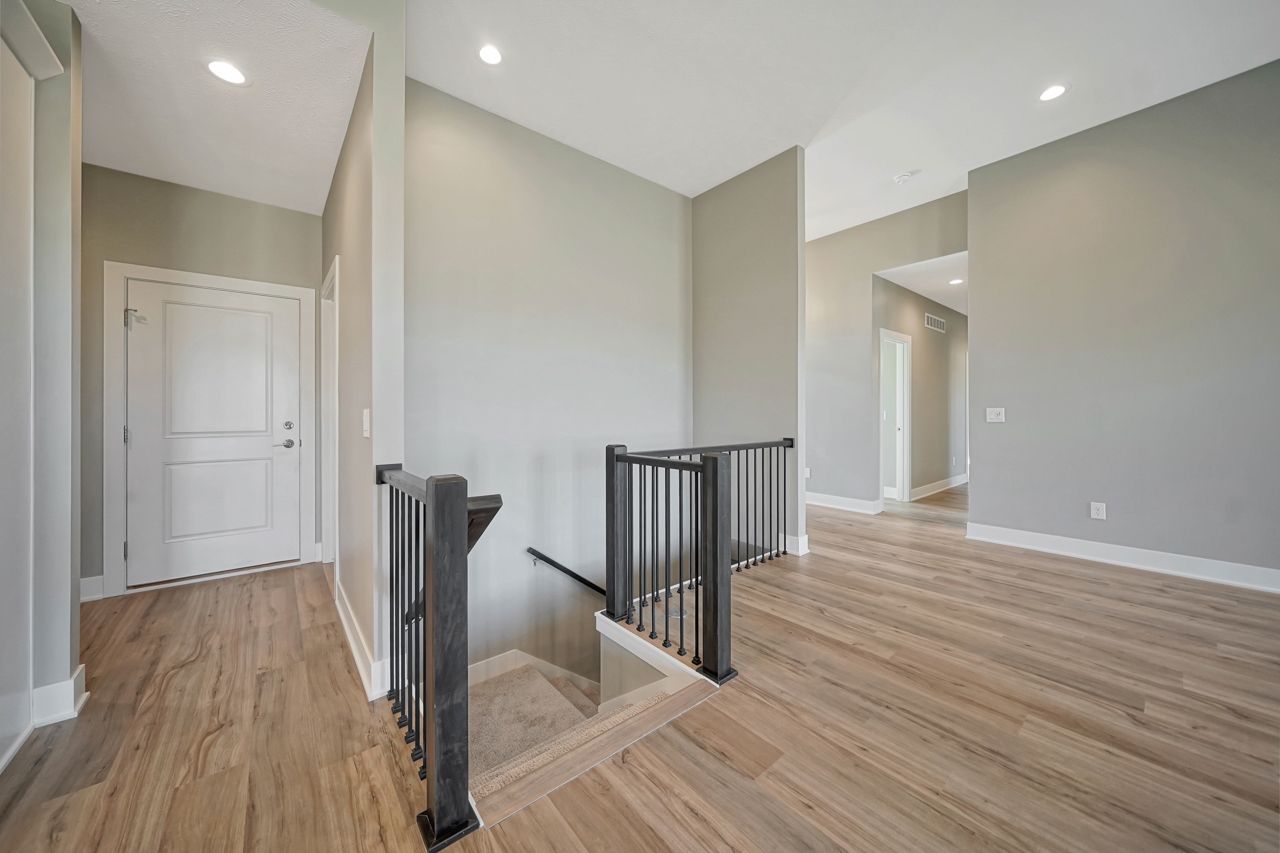 A hallway with hardwood floors and stairs in a house.