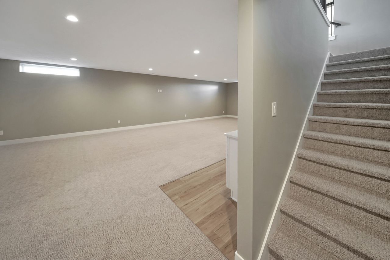 An empty basement with stairs leading up to the second floor.