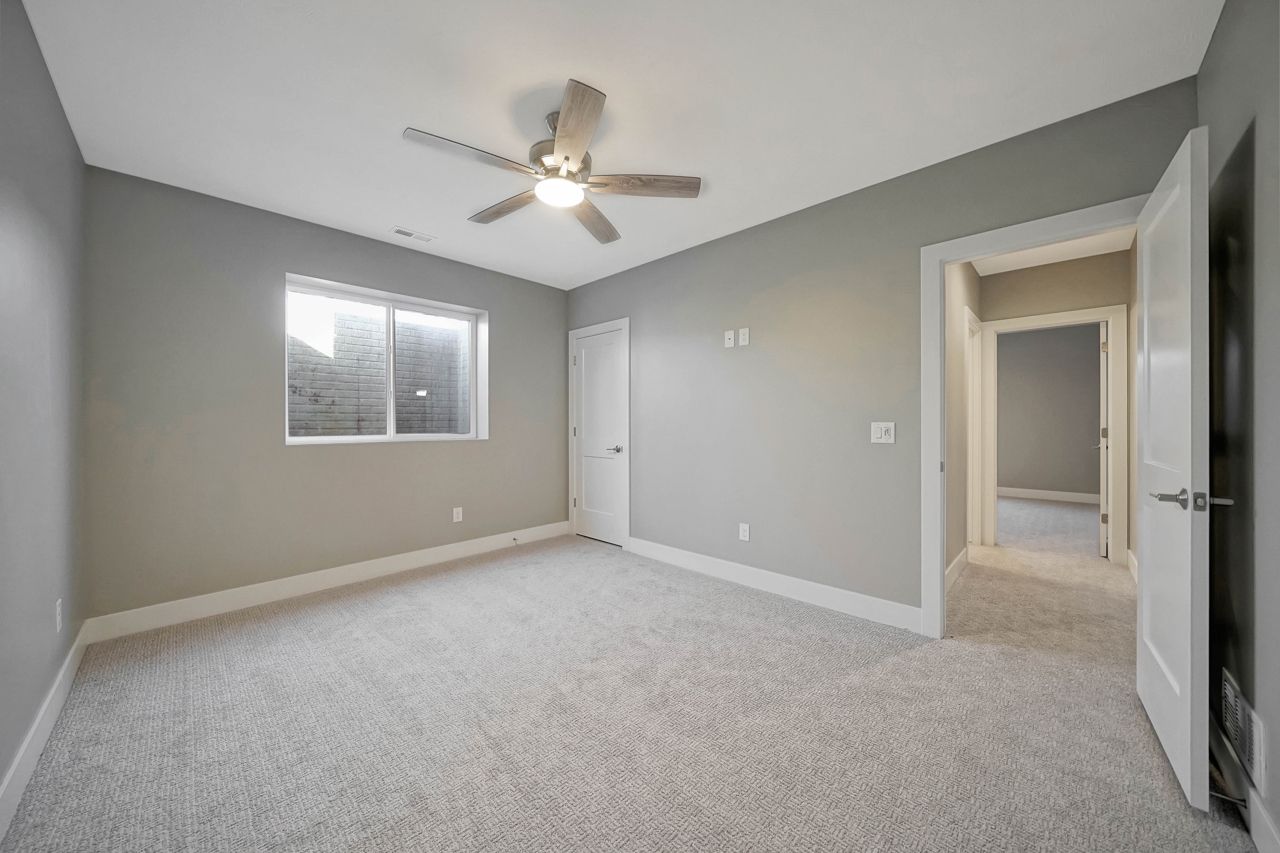 An empty bedroom with a ceiling fan and a window.