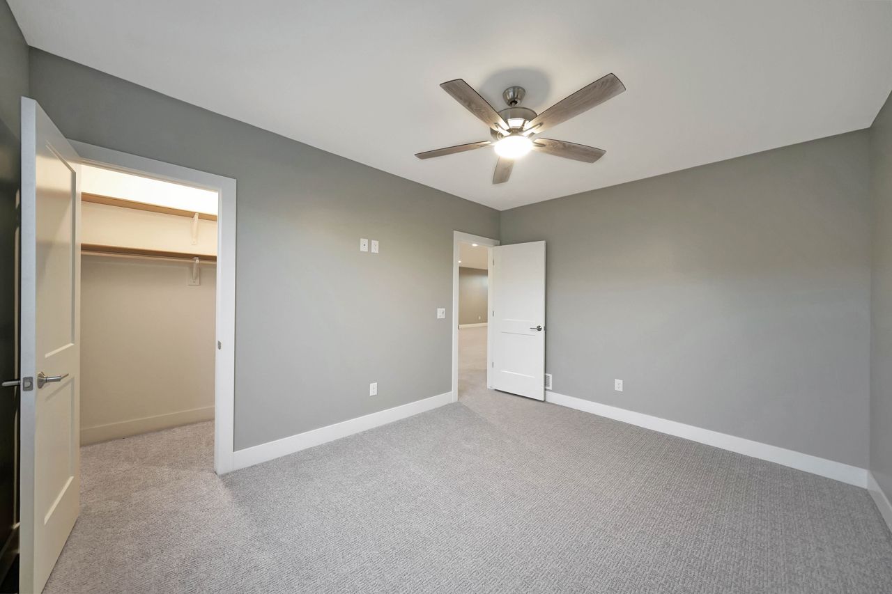 An empty bedroom with a ceiling fan and a walk in closet.