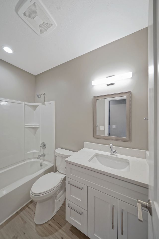 A bathroom with a toilet , sink , bathtub and mirror.