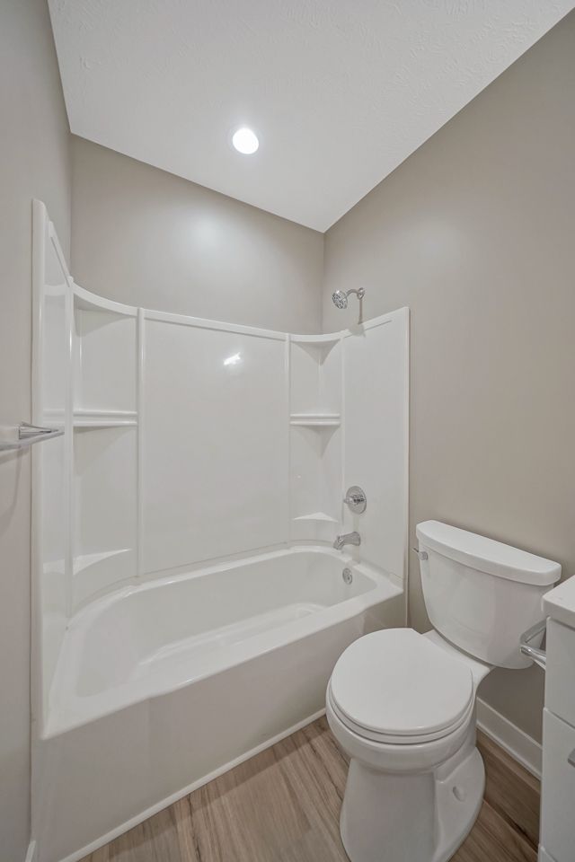 A bathroom with a toilet , bathtub and shower.