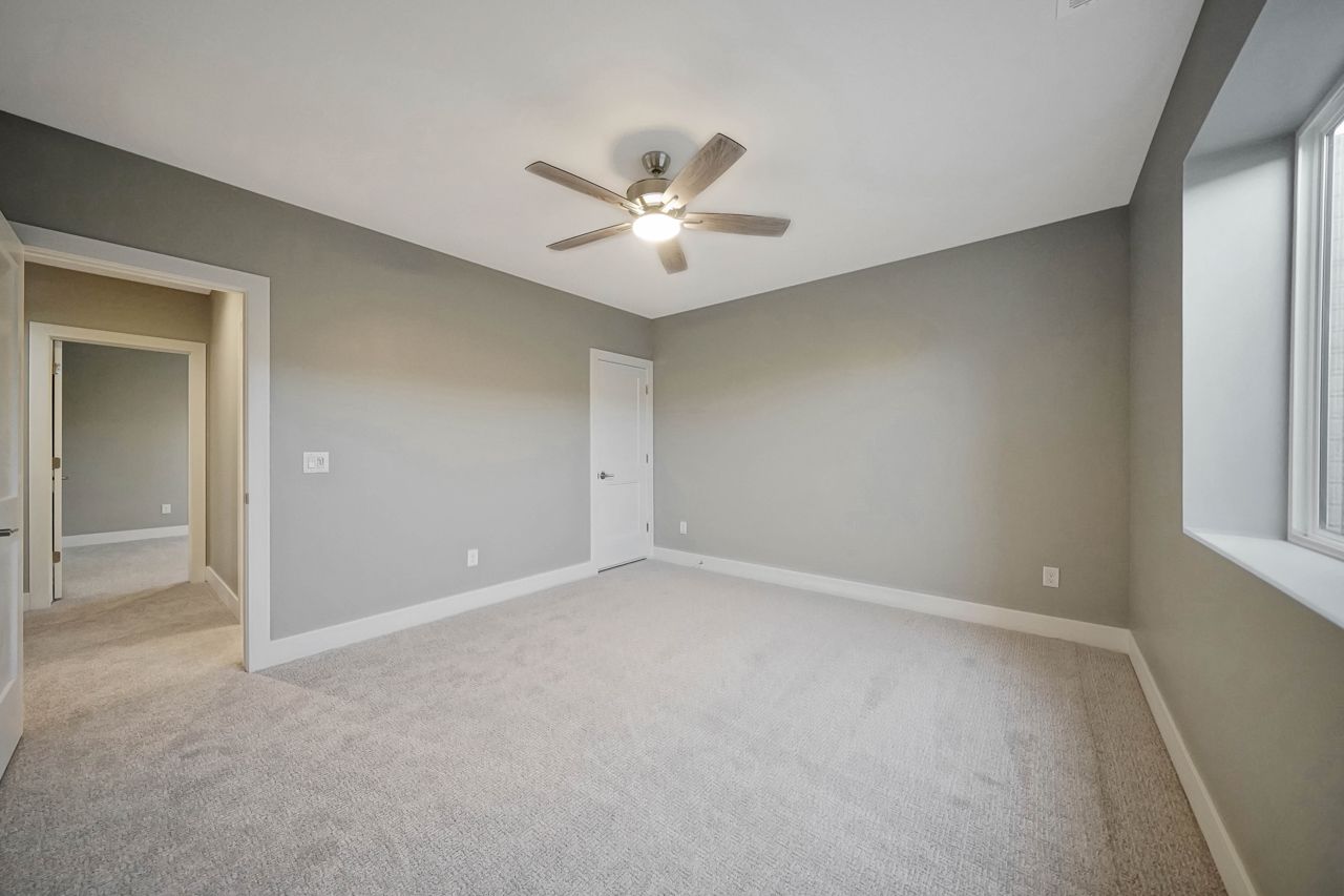 An empty bedroom with a ceiling fan and a window.