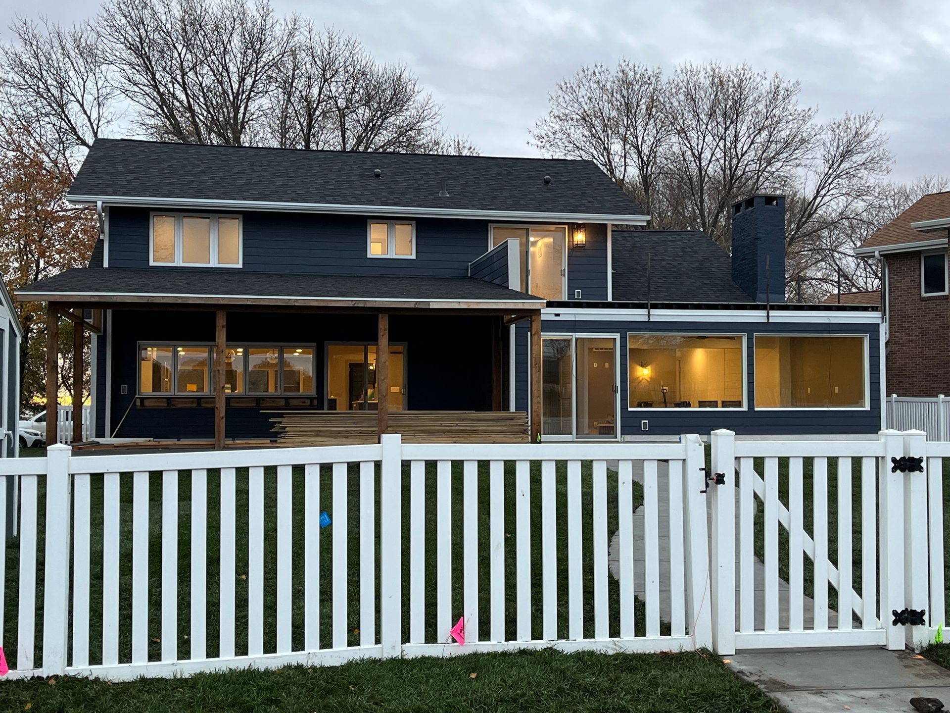 A two-story blue house with a white picket fence. A wooden porch spans the first floor.