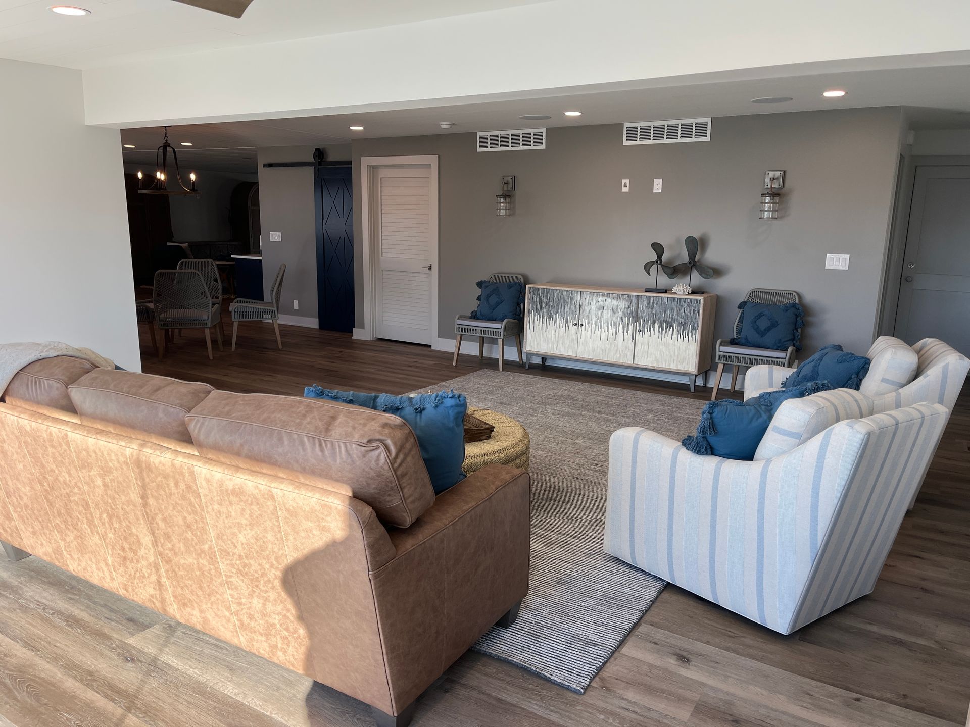 A living room with two sofas, a rug, and decorative wall sconces against a gray wall.