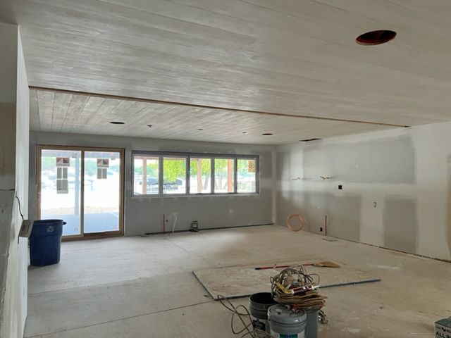 Interior of a room under construction with exposed wood ceiling and drywall walls. 