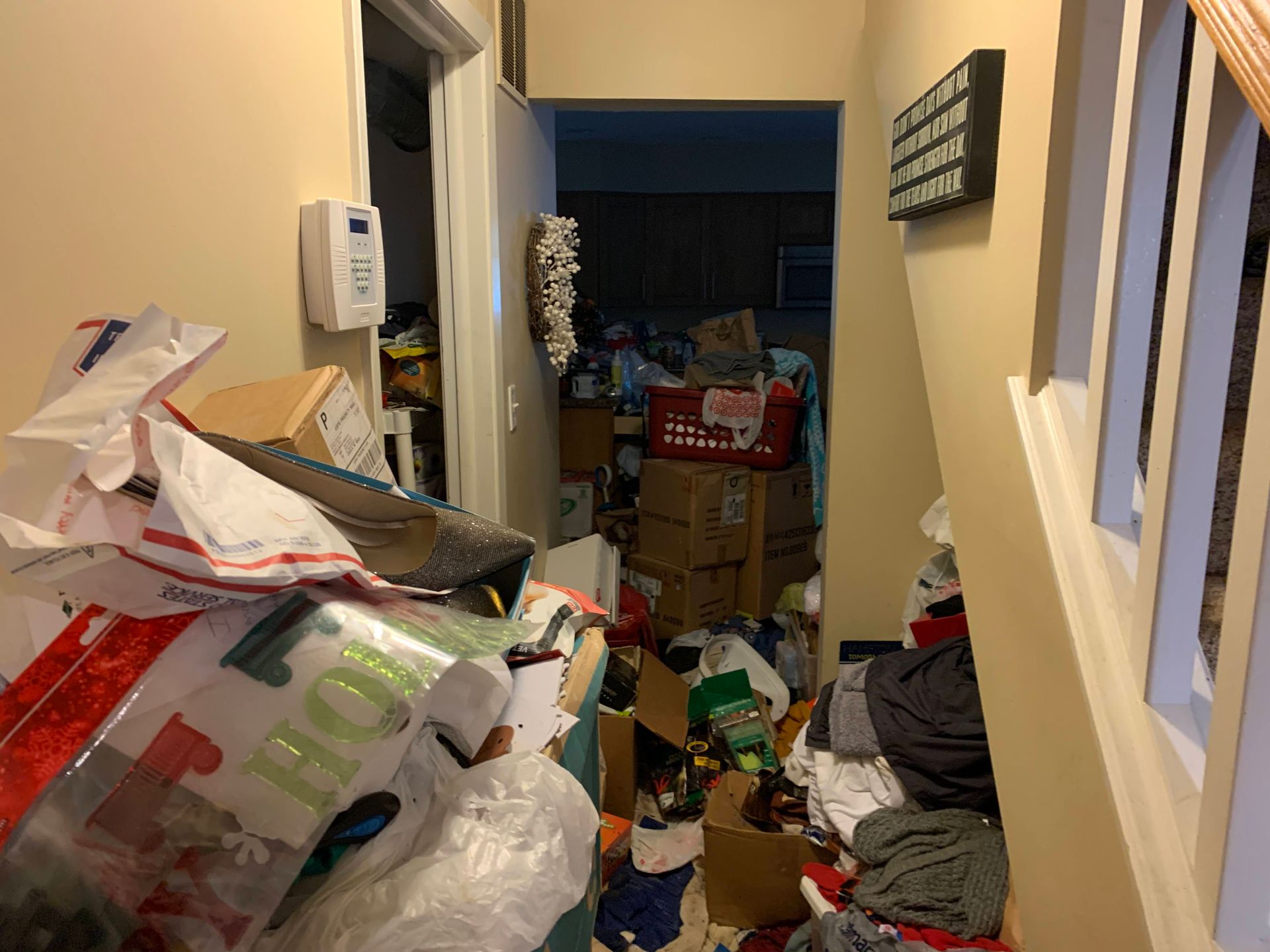 Cluttered hallway filled with boxes, bags, and other items, blocking the path to another room. 