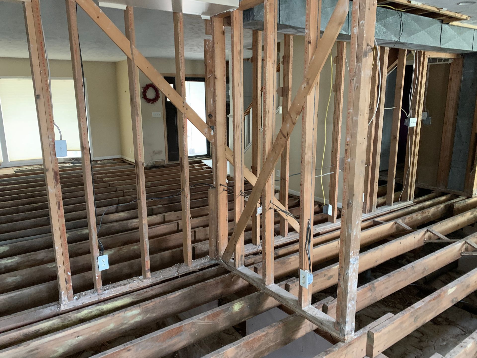 Interior view of a house undergoing renovation, with exposed wooden framing and electrical boxes.