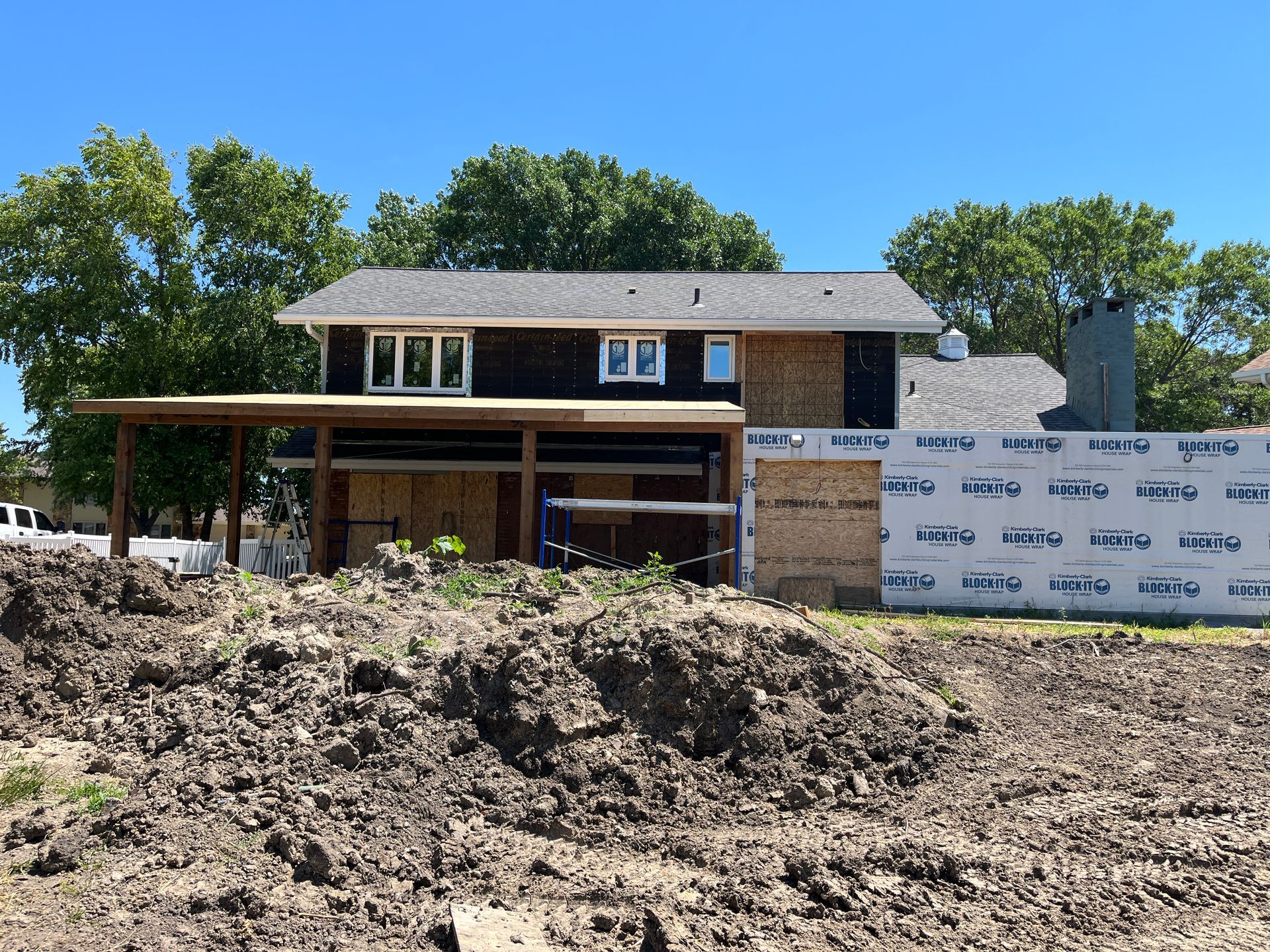 A two-story house under construction; black siding, unfinished walls. A covered patio is partially built on the left.