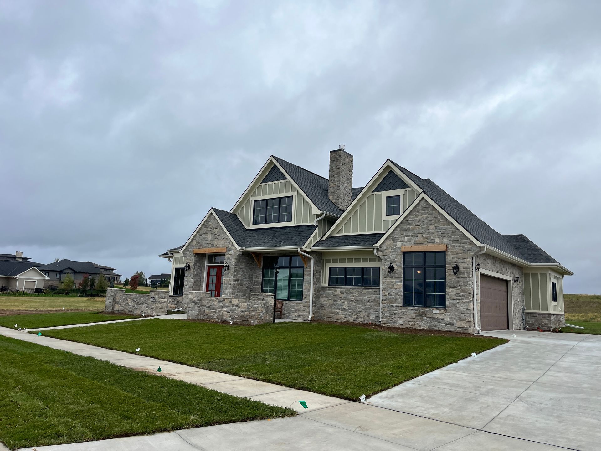 A large house with a lot of windows is sitting on top of a lush green field.
