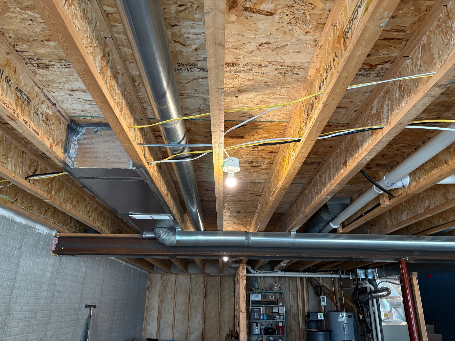 Basement ceiling with exposed wooden beams, ductwork, electrical wiring, and a lightbulb.