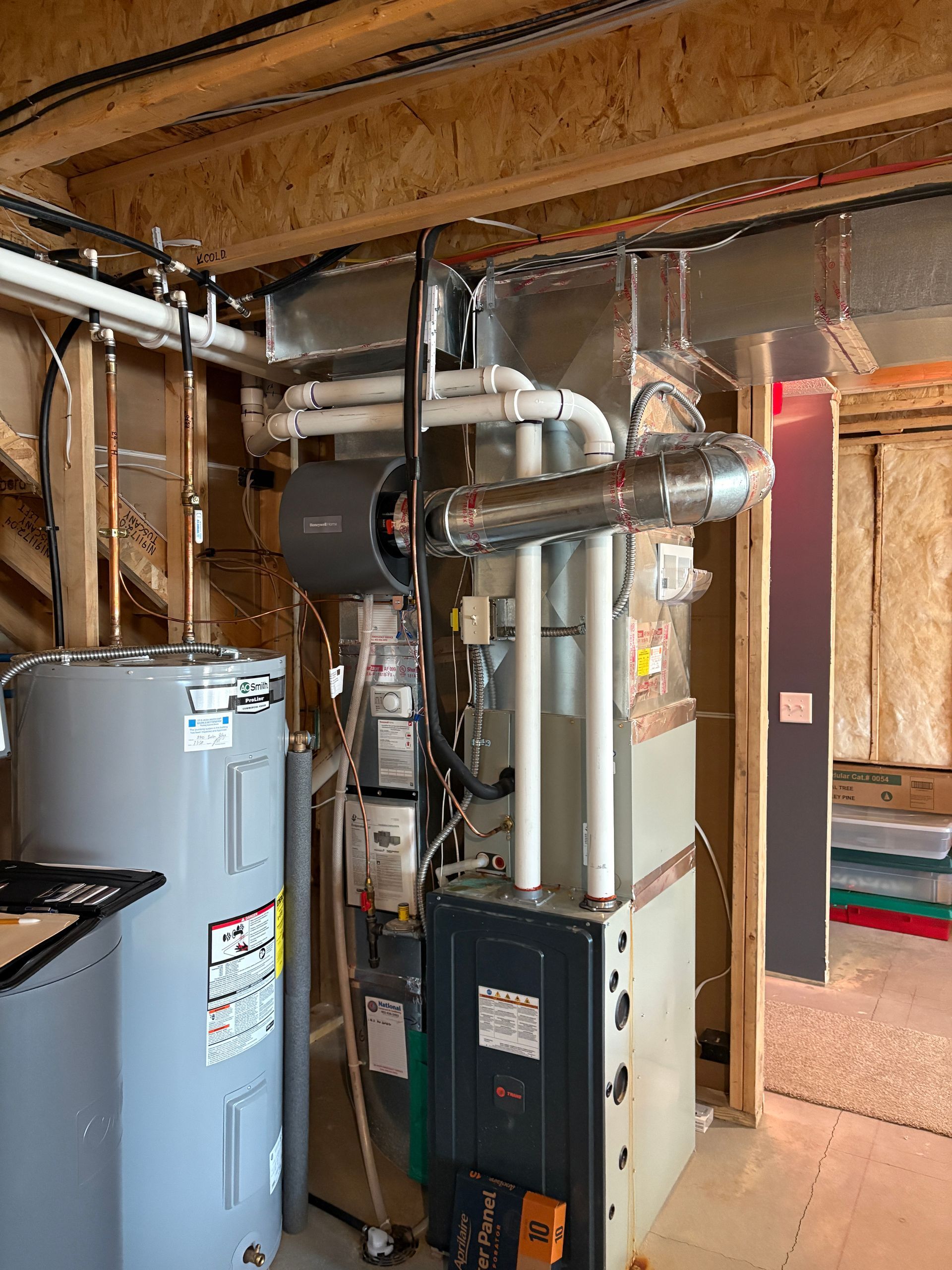 Furnace and water heater in a basement. Metal ductwork and pipes. Unfinished walls.