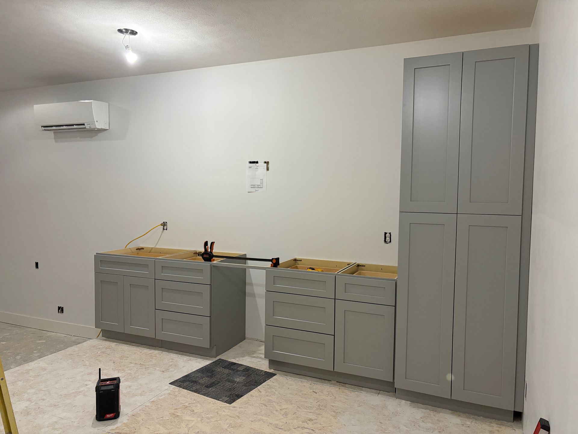 A room with gray cabinets and white walls is being remodeled.