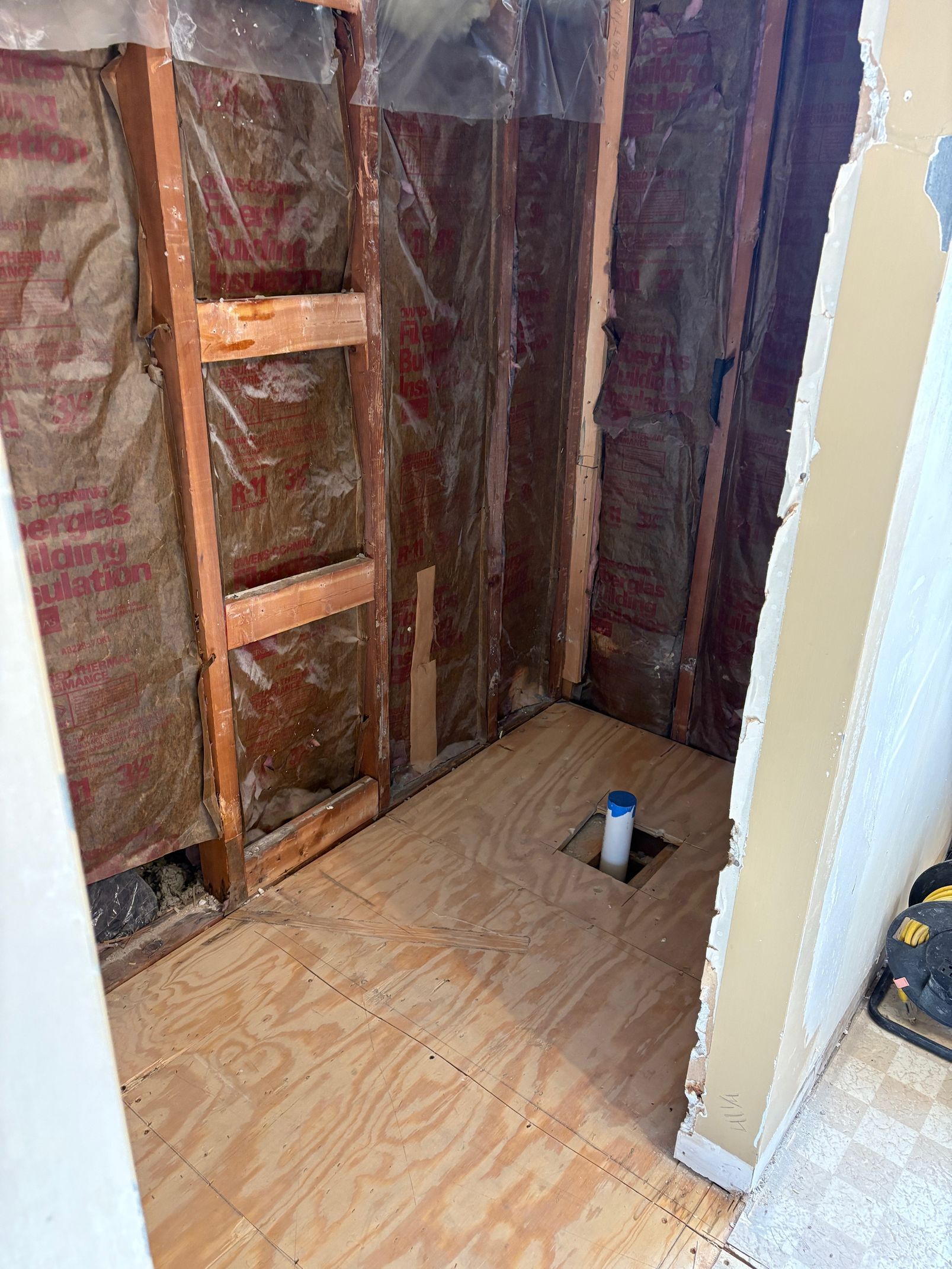 A bathroom under construction with a ladder and a hole in the floor.