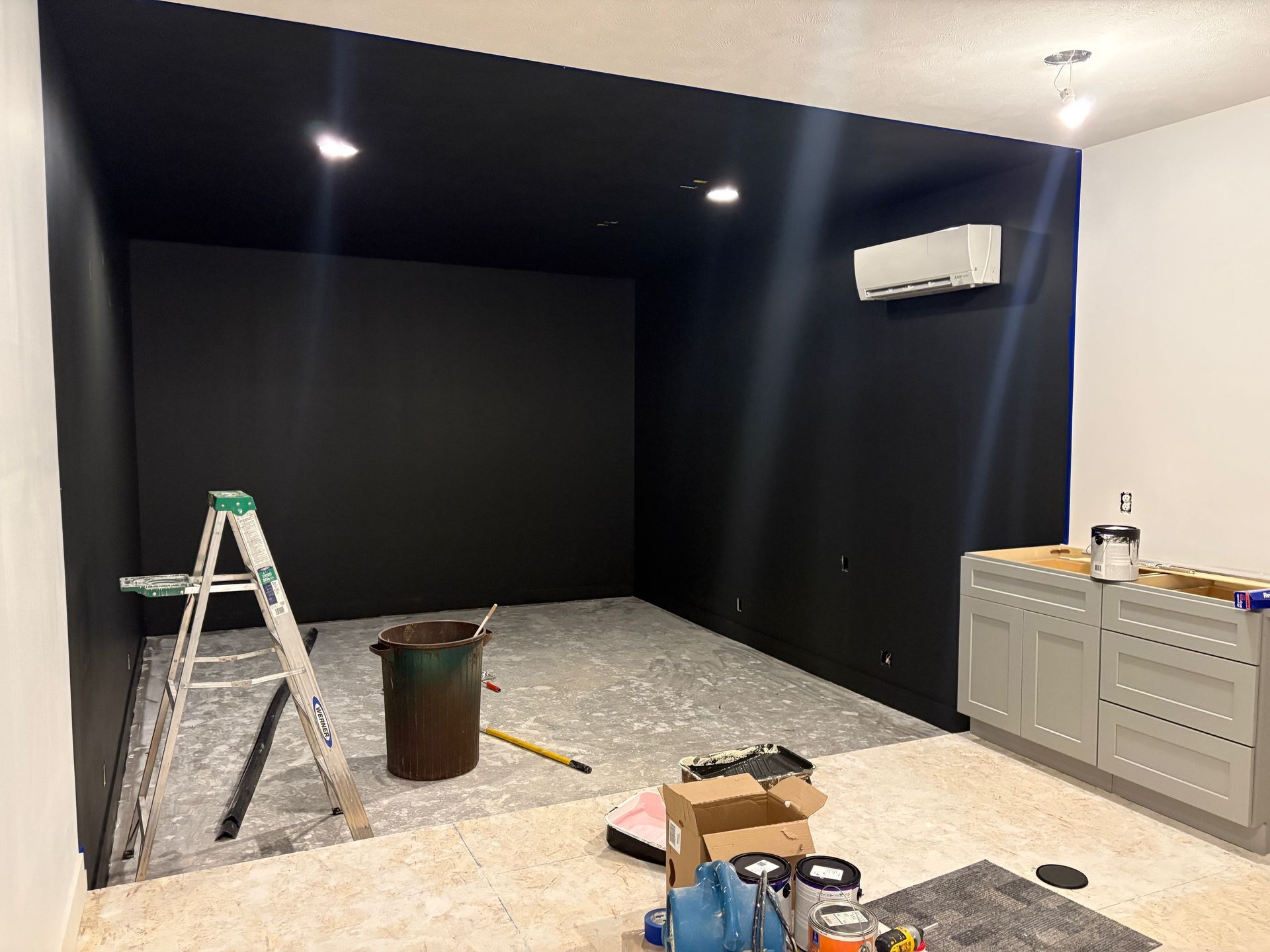 A room with a black wall and a ladder in it.