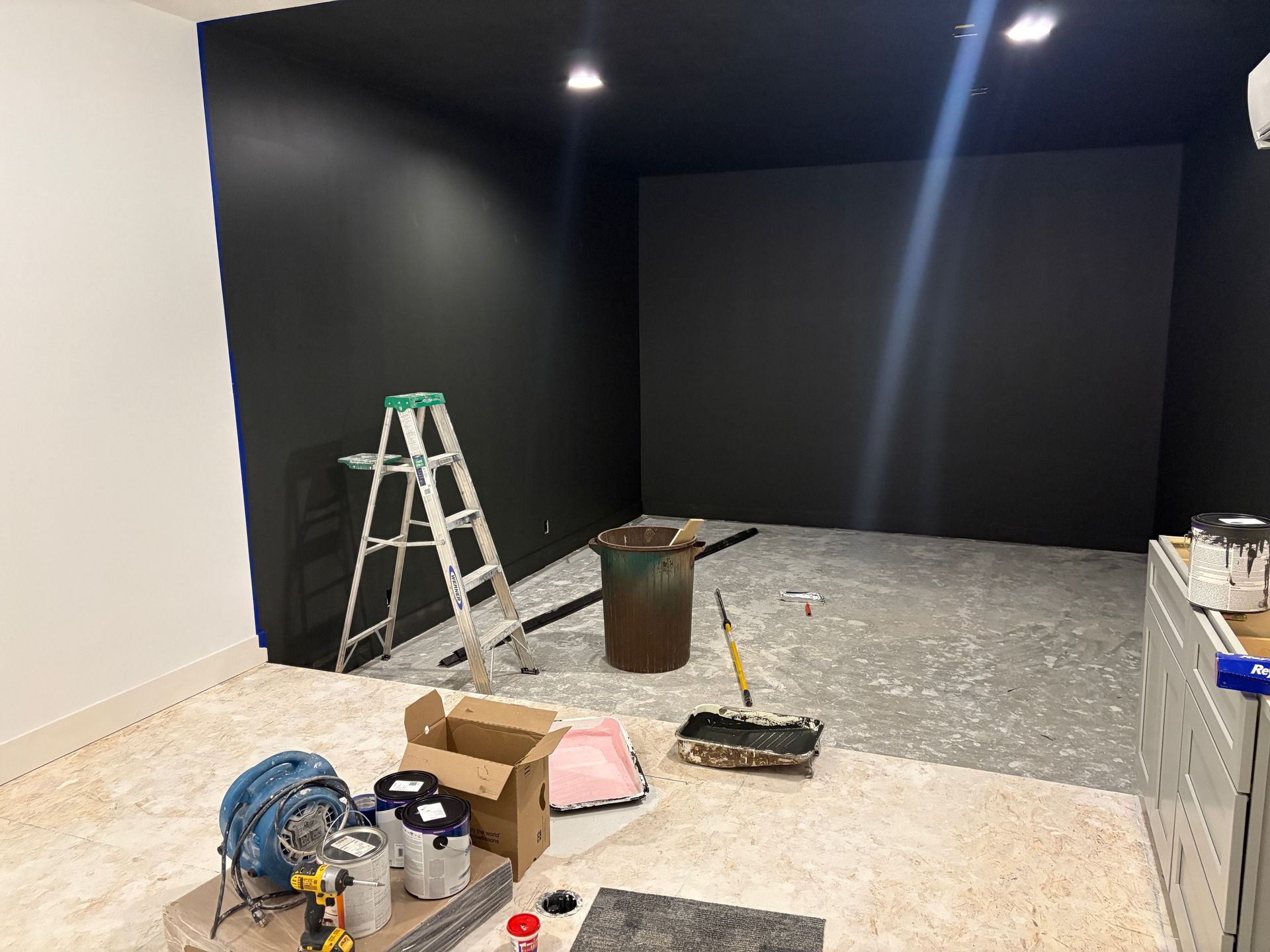A room with a black wall and a ladder in it.