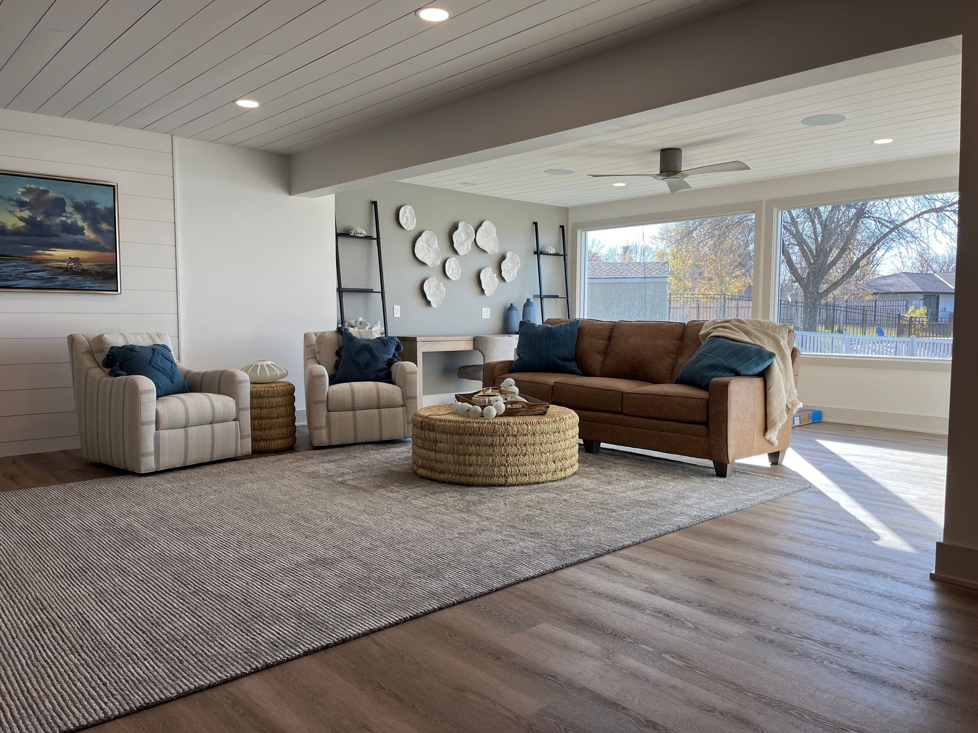 Living room with two armchairs, a sofa, rug, coffee table, and large window.