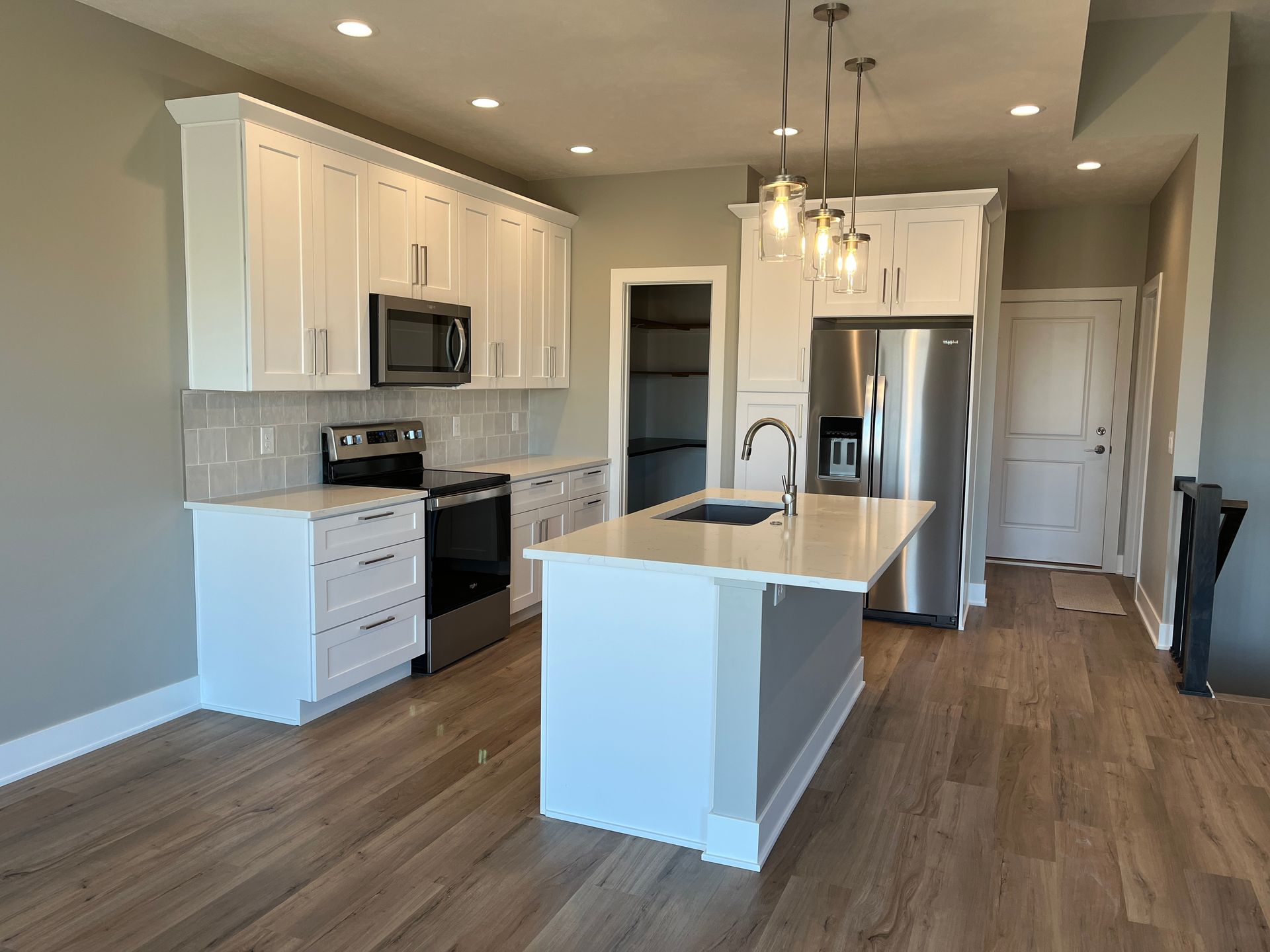 A kitchen with white cabinets, stainless steel appliances, and a large island.