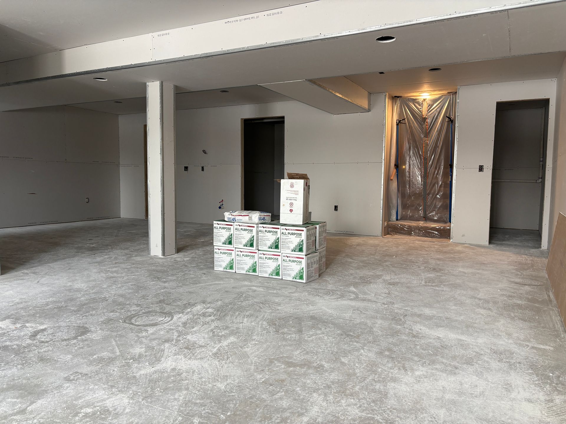An unfinished interior space with drywall and boxes on the floor.