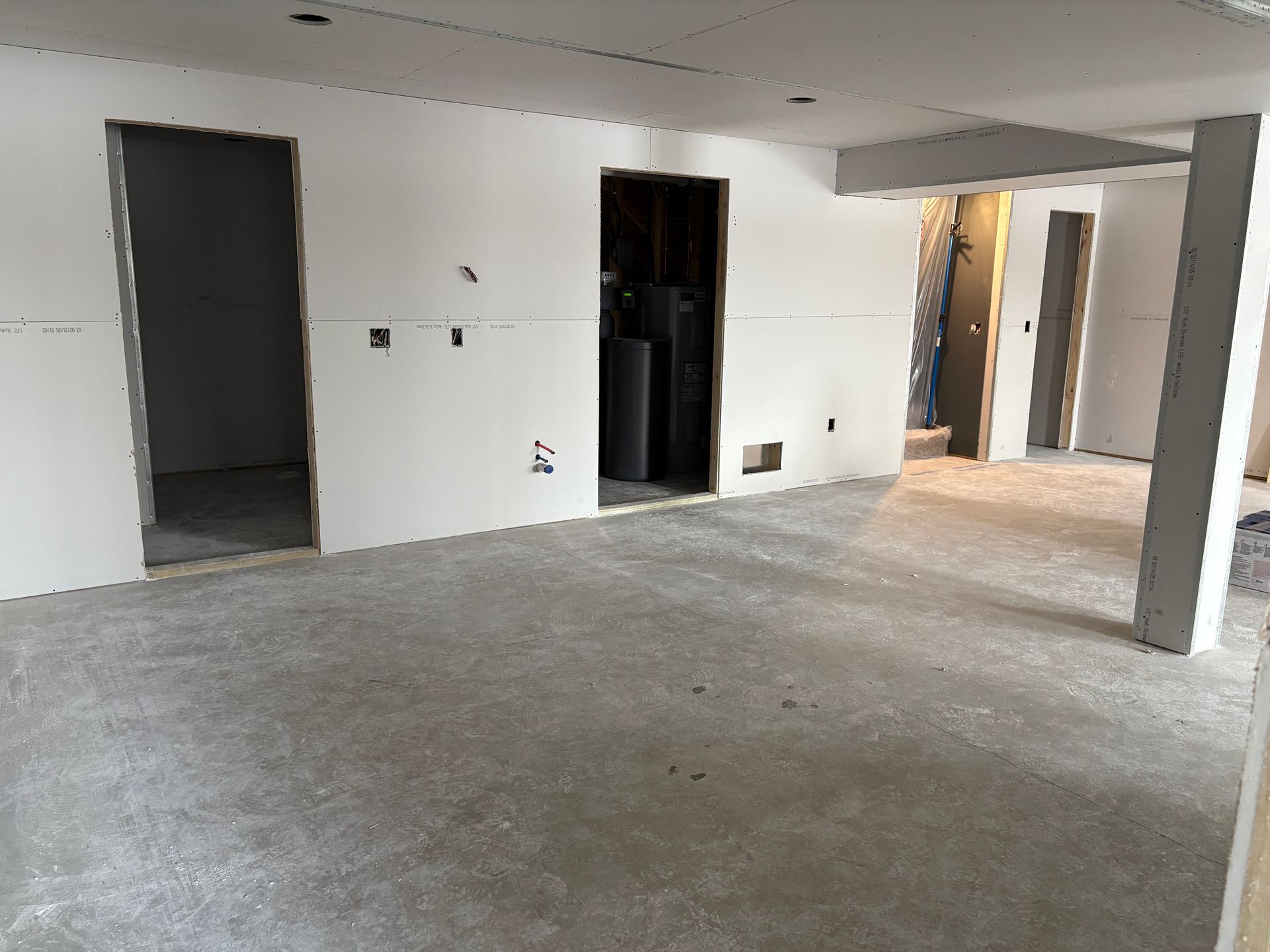 Interior of a room under construction with unfinished walls, doorways, and a concrete floor.