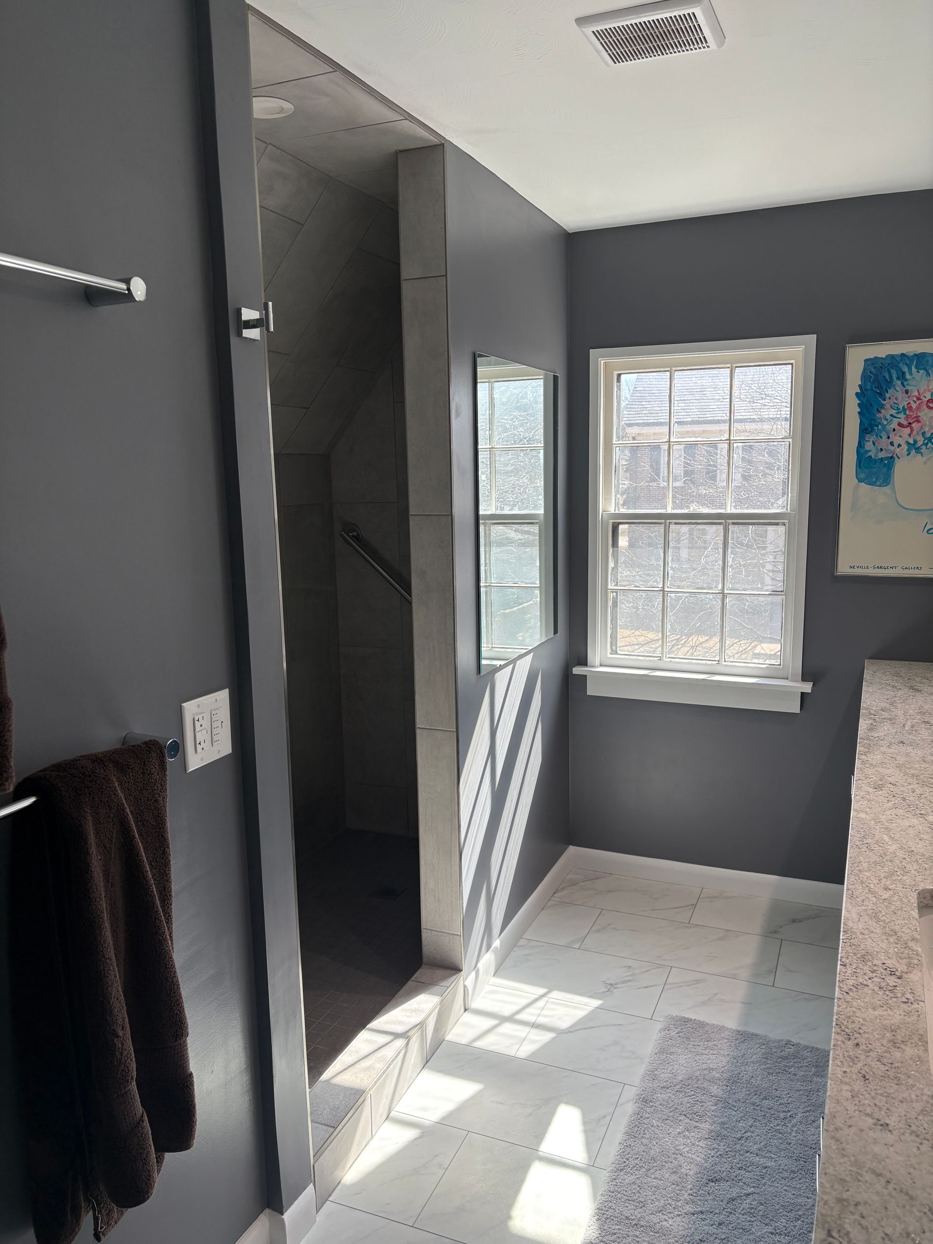A bathroom with gray walls and a large window