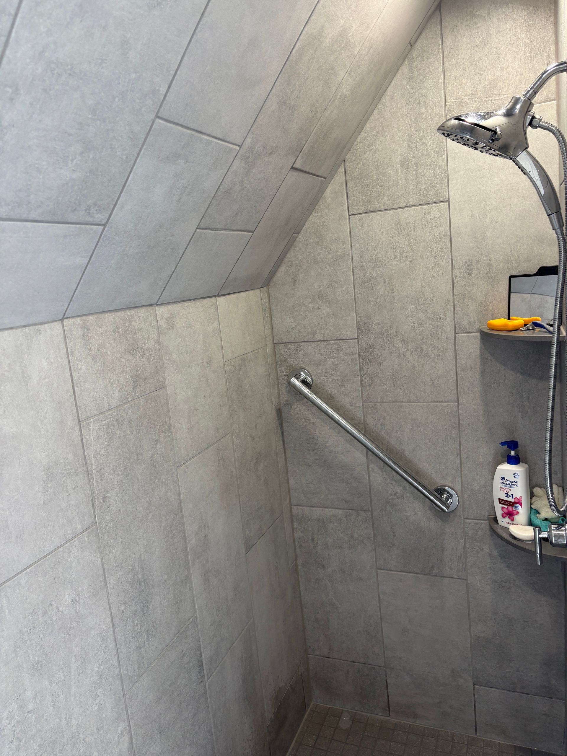 A shower with a hand rail and a shower head.