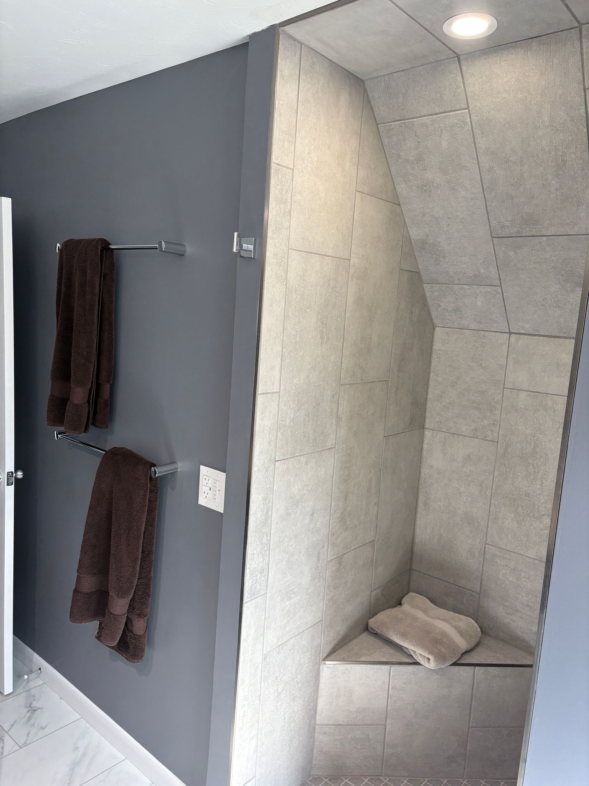 A bathroom with a walk in shower and a corner bench