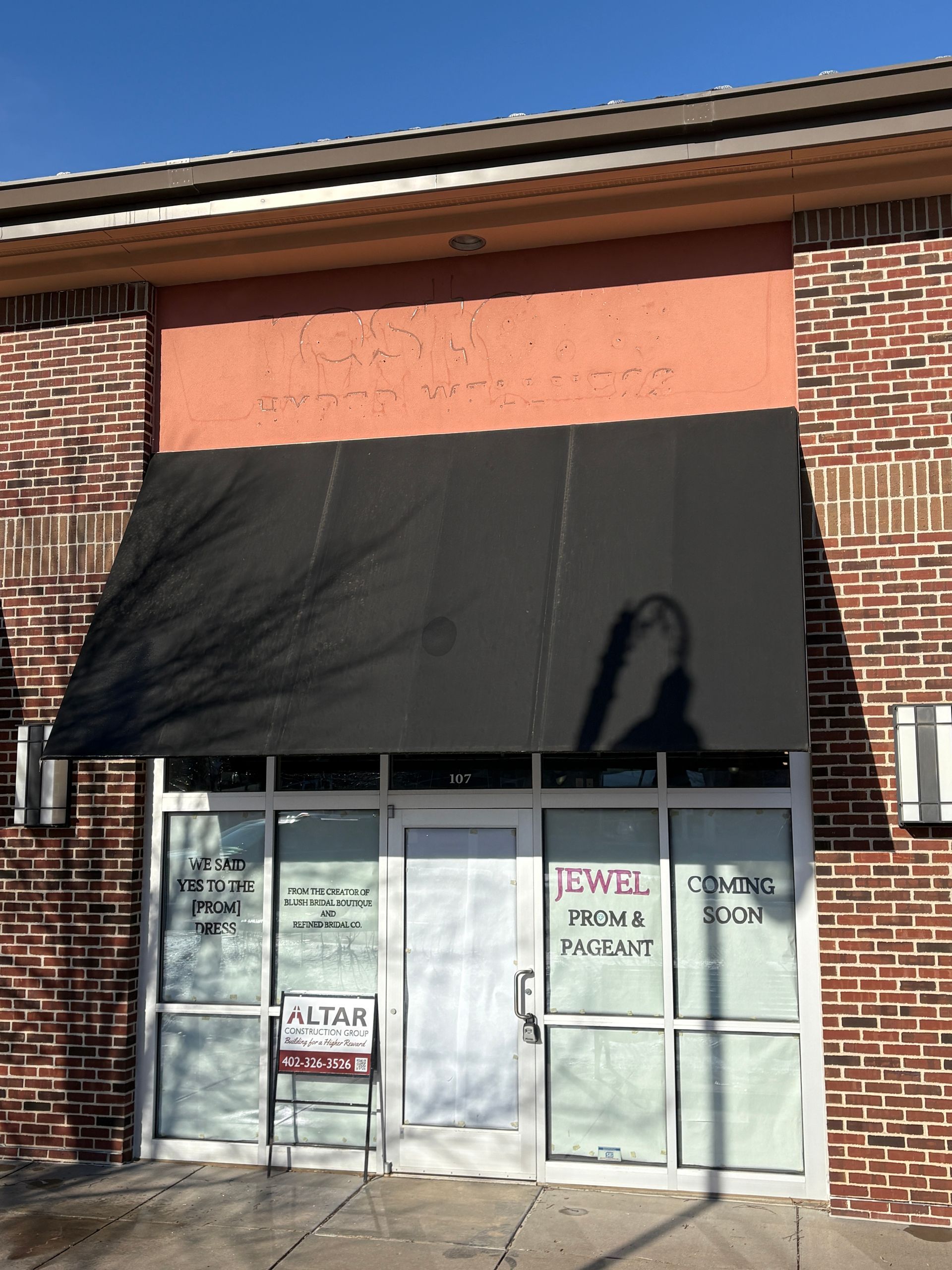 Storefront with black awning, brick exterior, and 