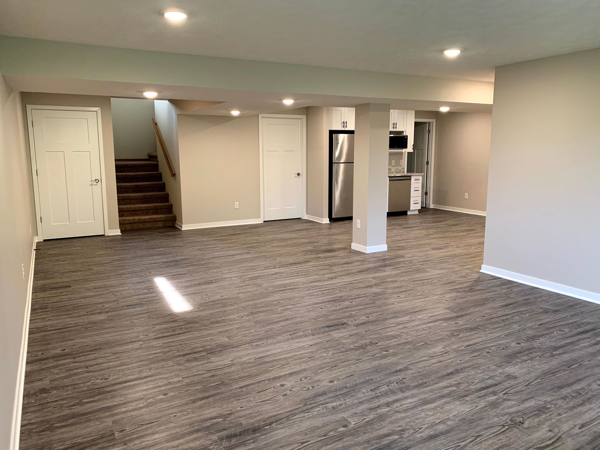 A large empty basement with hardwood floors and a staircase leading to the second floor.