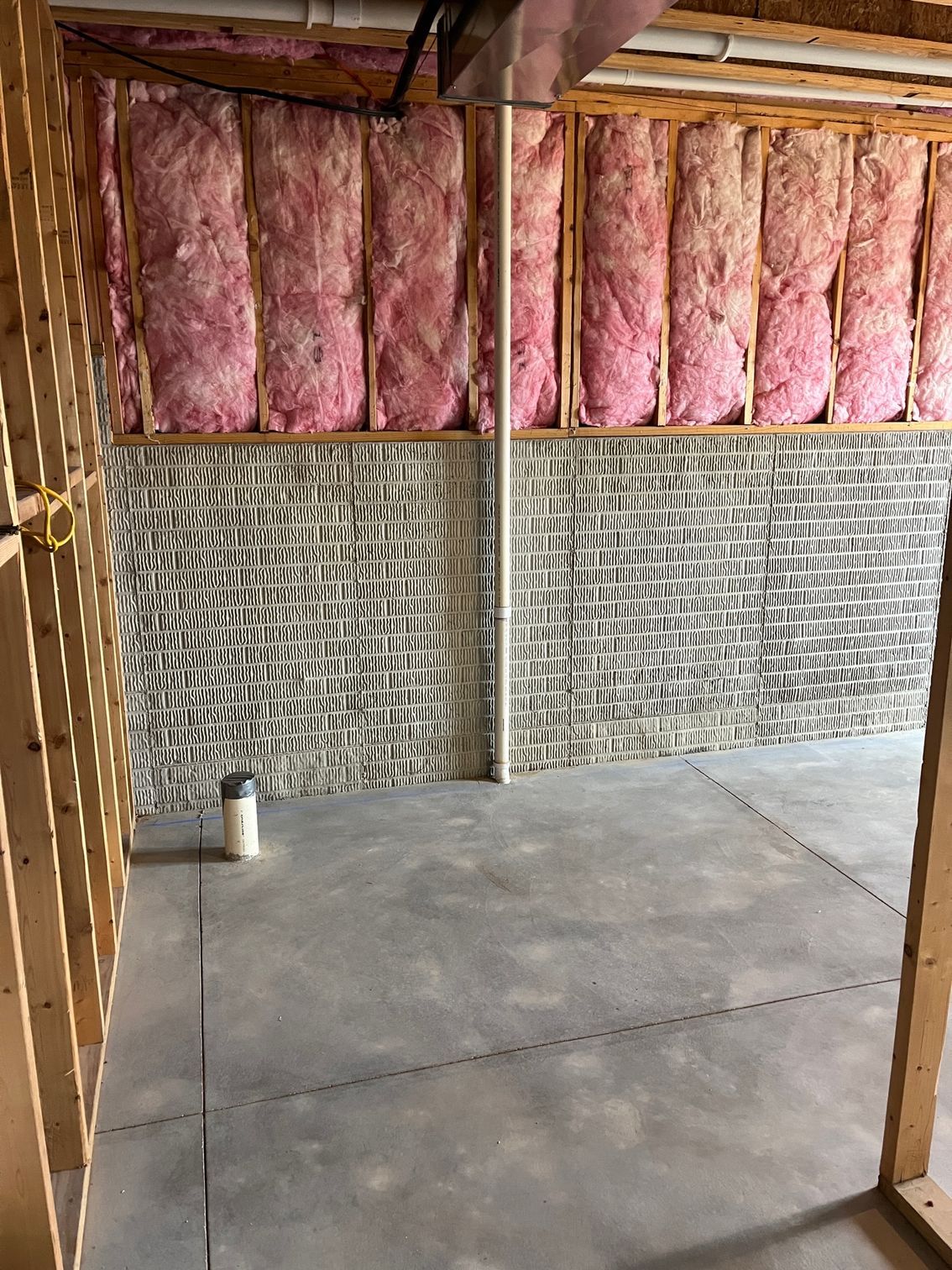 A room with a brick wall and pink insulation on the walls.
