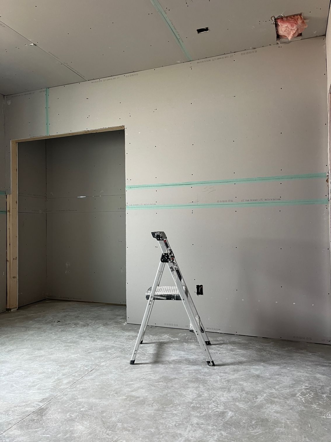 A ladder is leaning against a wall in a room under construction.