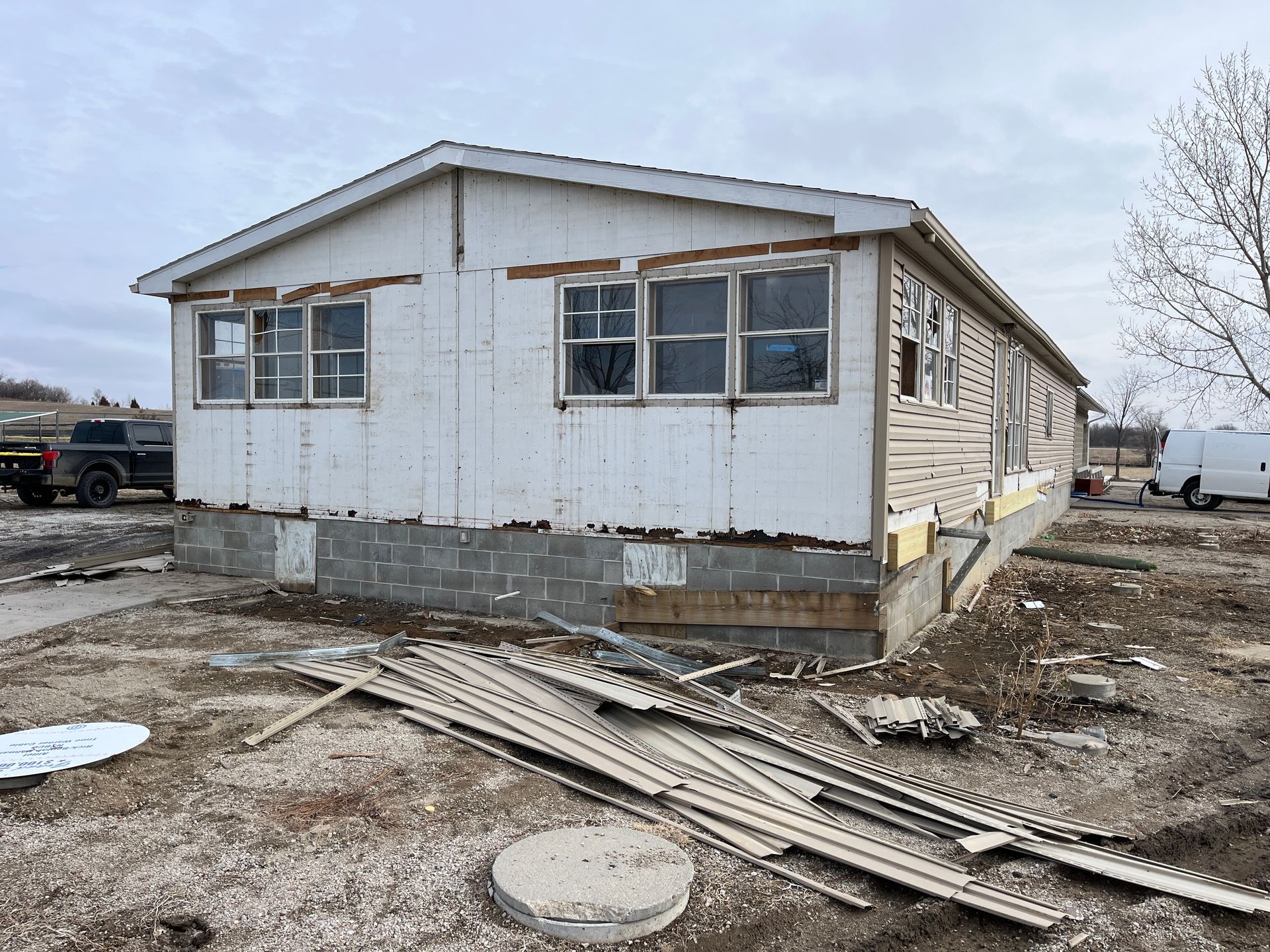 A mobile home is sitting in the middle of a dirt field.
