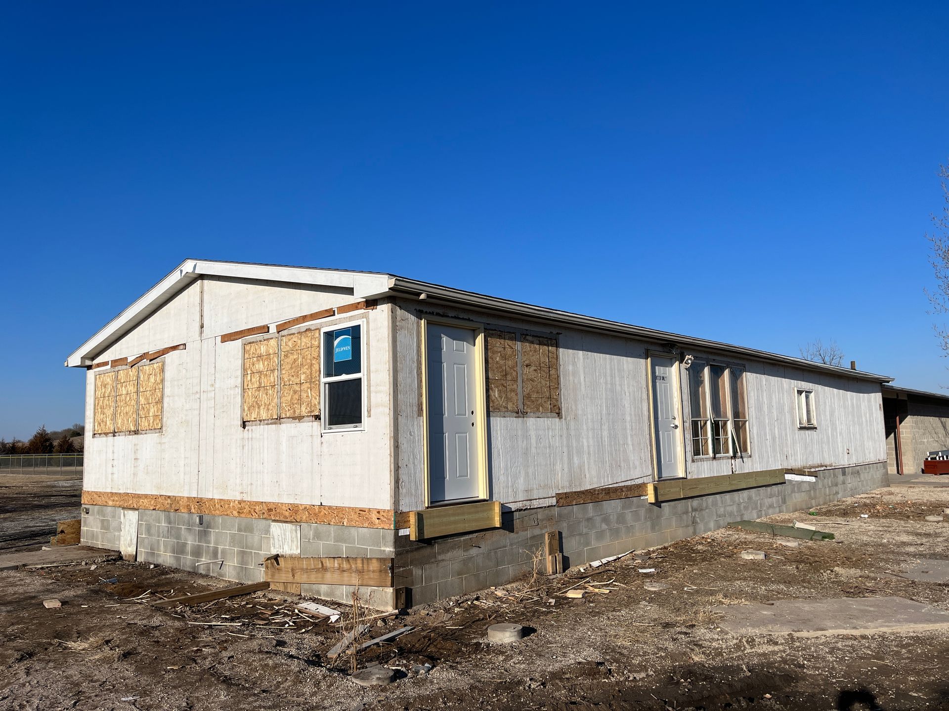 A mobile home is sitting in the middle of a dirt field.
