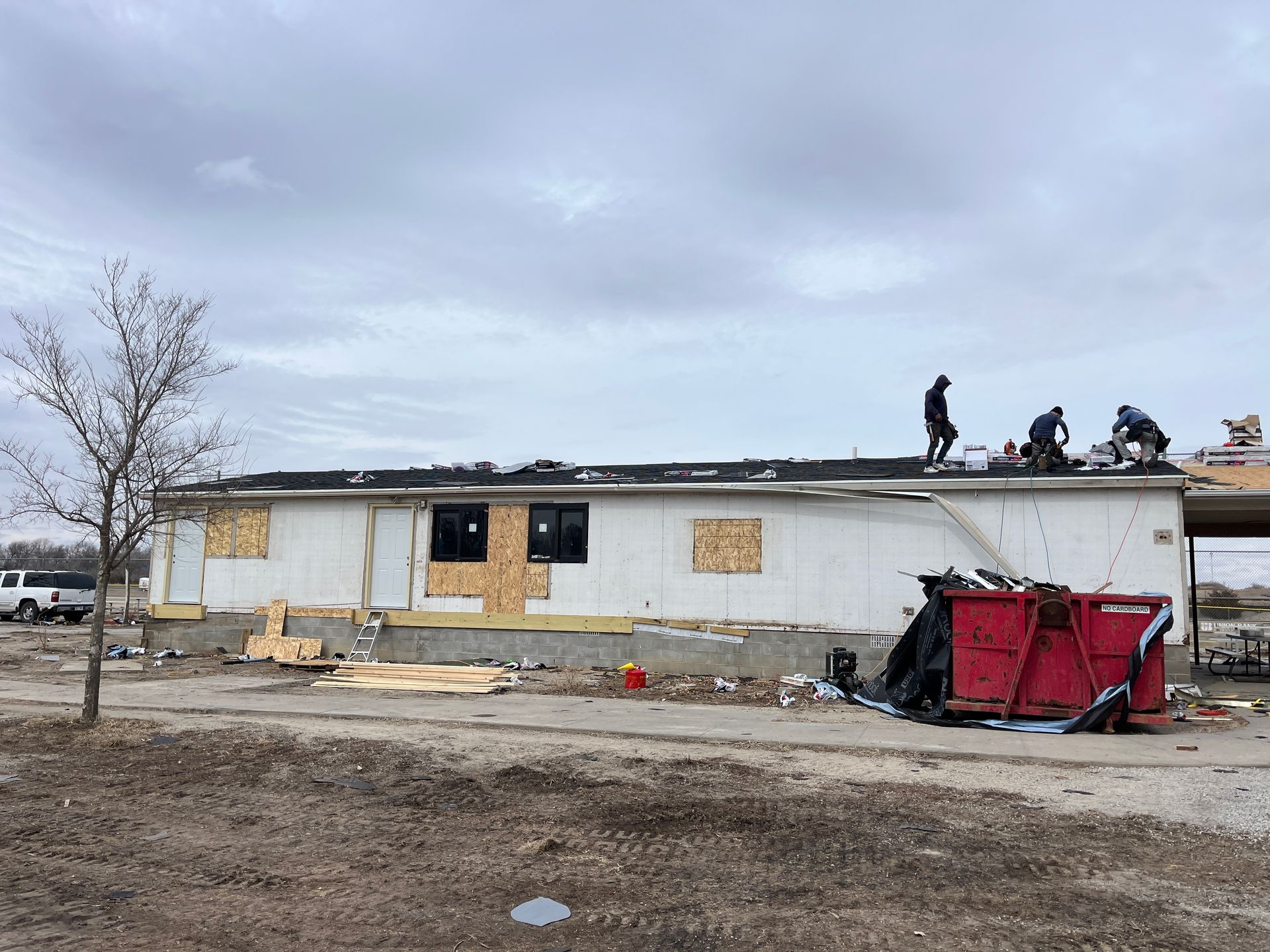 A group of people are working on the roof of a house.