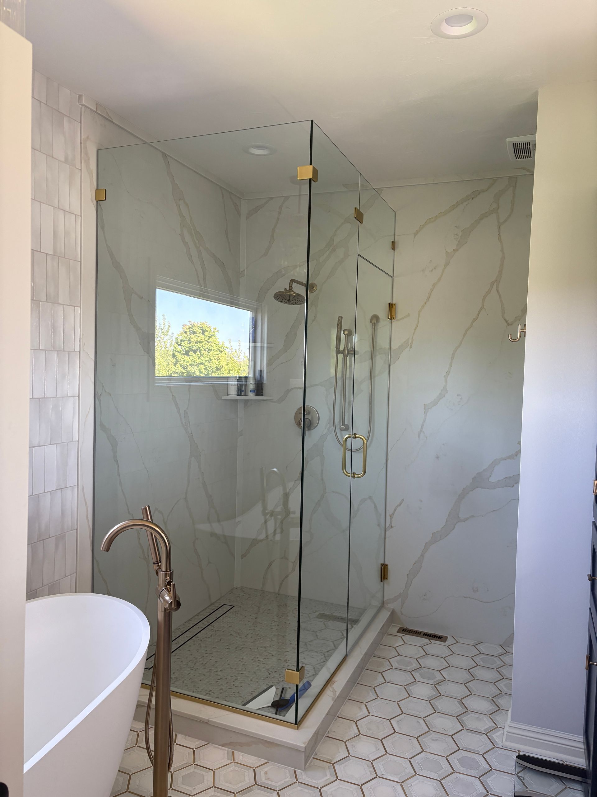 Luxurious bathroom with a glass shower enclosure and marble-look tile.