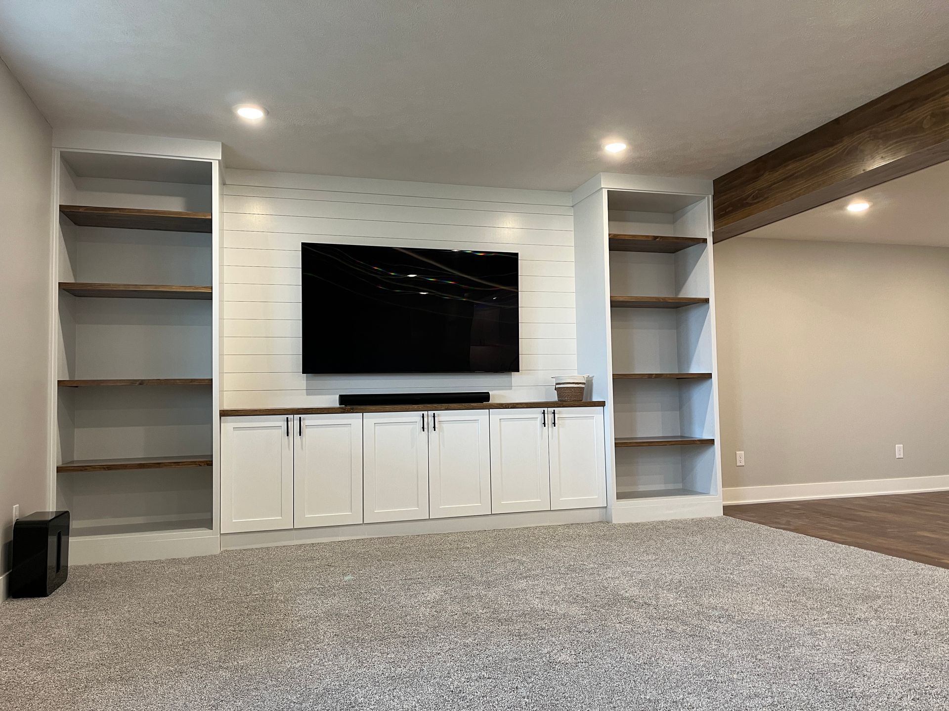 A living room with a flat screen tv on the wall and shelves.