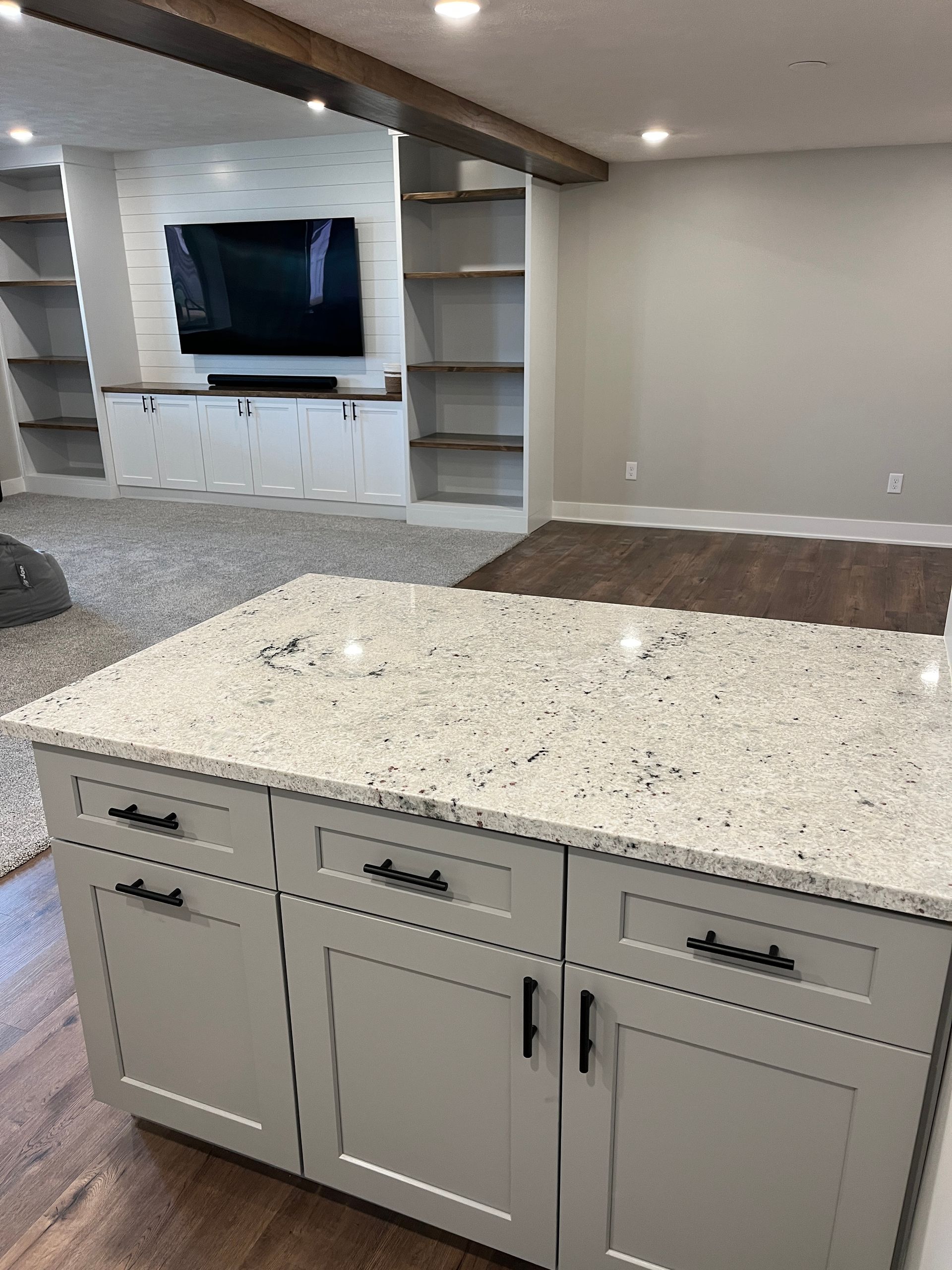 A kitchen with a large island and a flat screen tv on the wall.