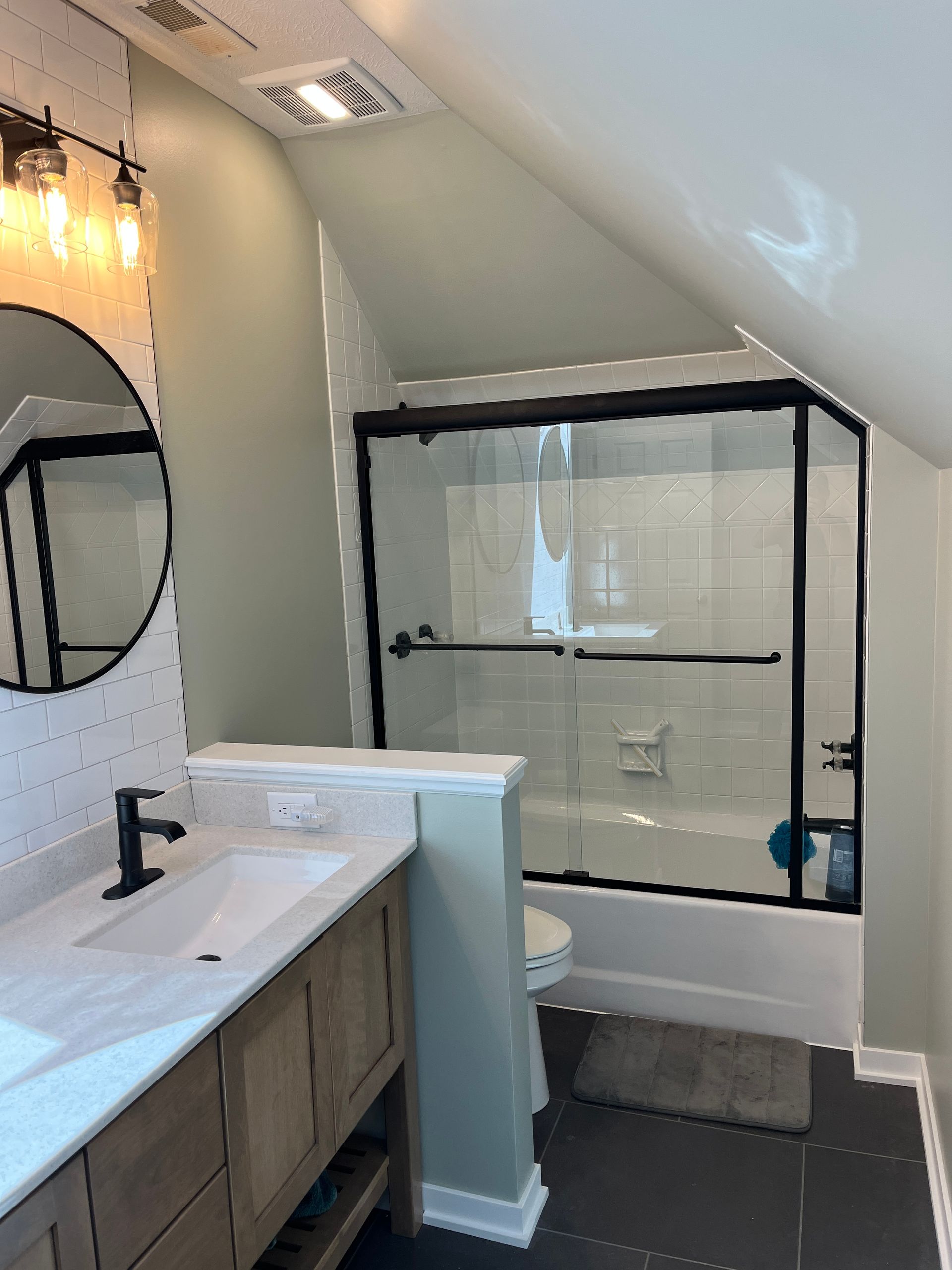 A bathroom with a sink , toilet , shower and mirror.