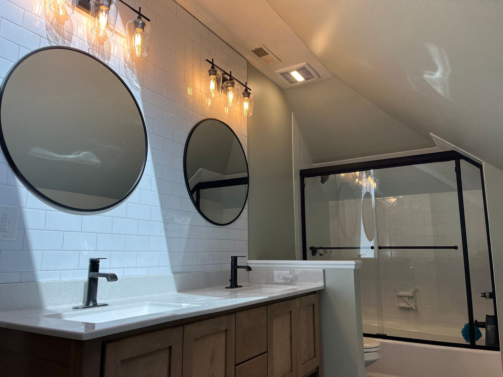 A bathroom with two sinks , two mirrors , a toilet and a shower.
