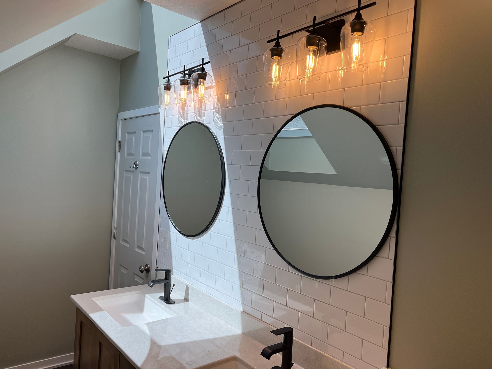 A bathroom with two sinks and two round mirrors.