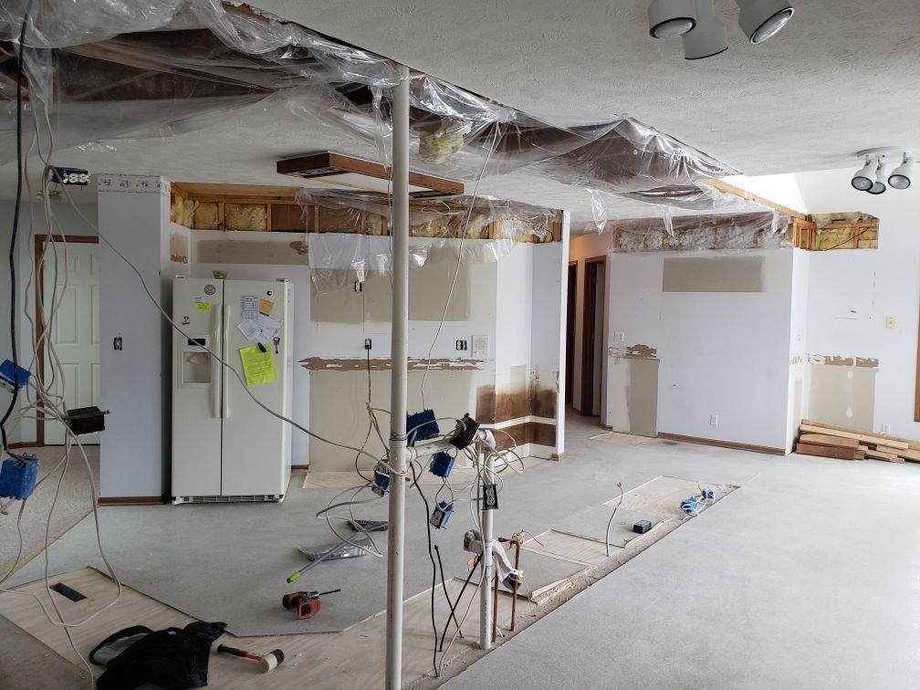An empty room with a refrigerator in the middle of it.