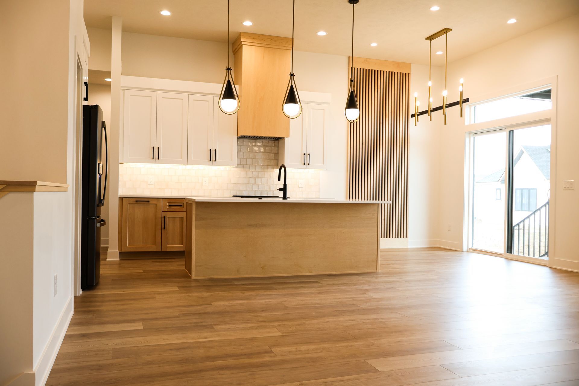 Modern kitchen with light wood cabinets, island, and hardwood floors.