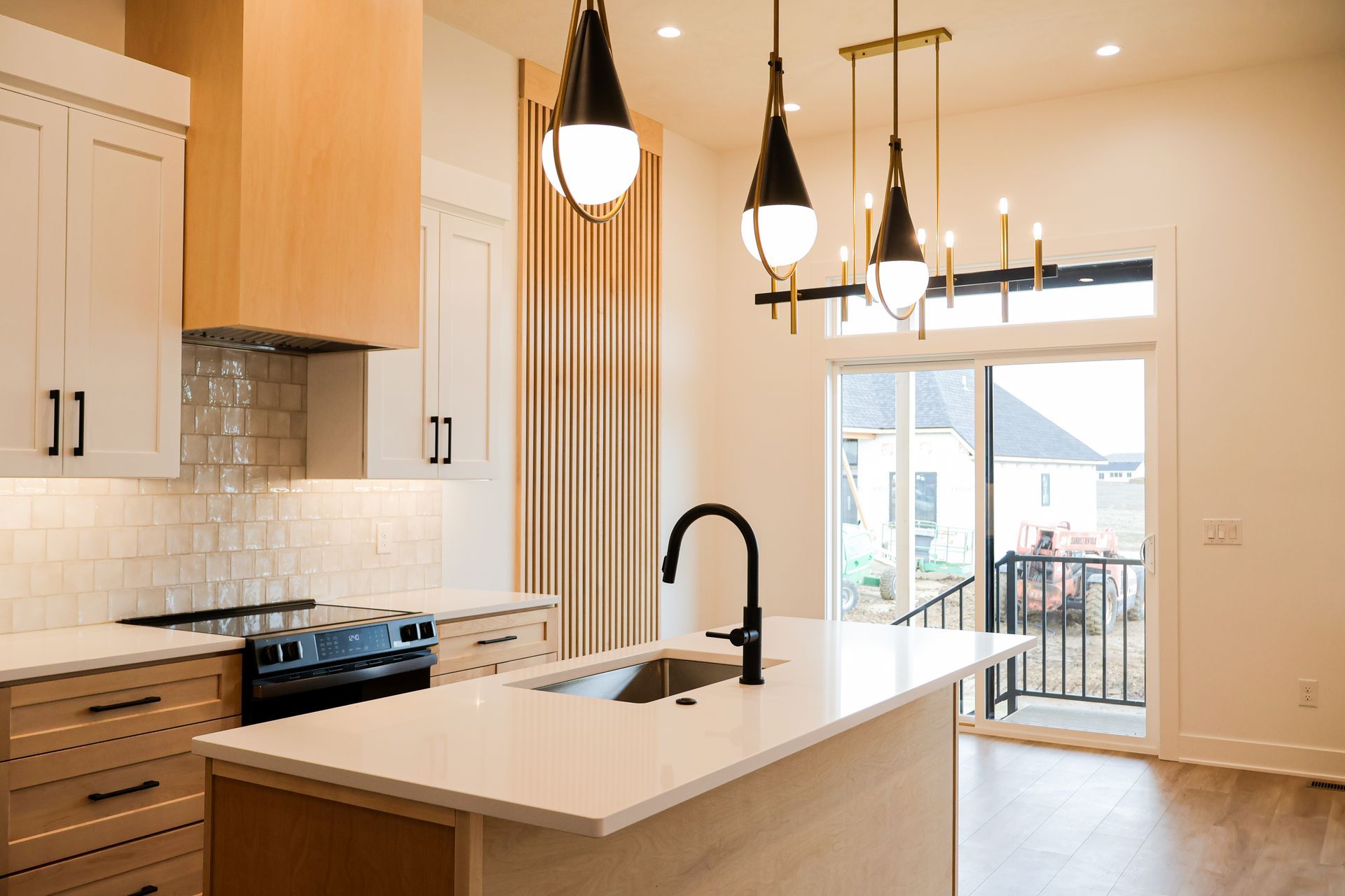 Modern kitchen with white countertops, black faucet, and pendant lights.