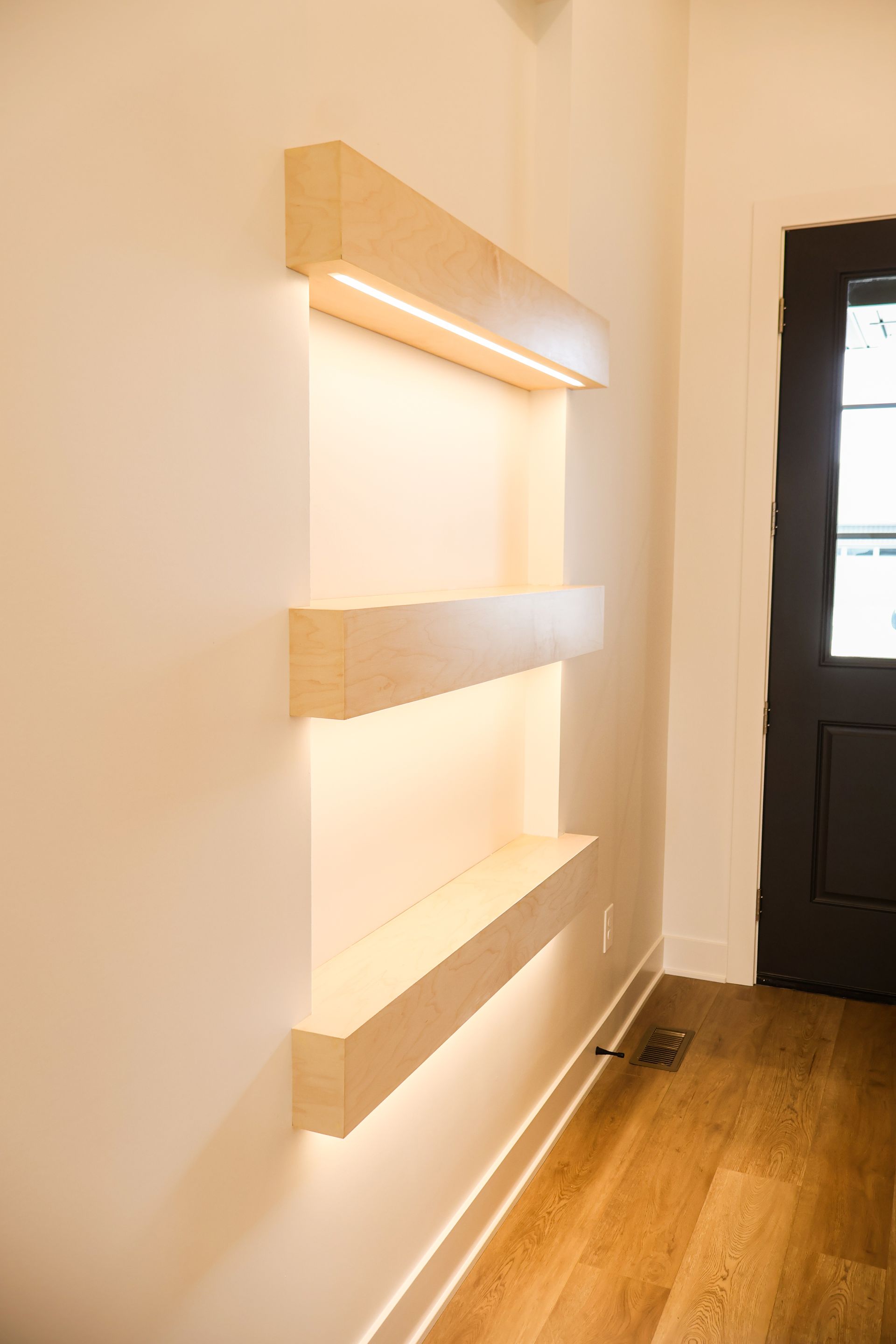 A carpeted bedroom with gray walls, white trim, a five-blade ceiling fan, a walk-in closet with wood shelves and an open door to a hall.