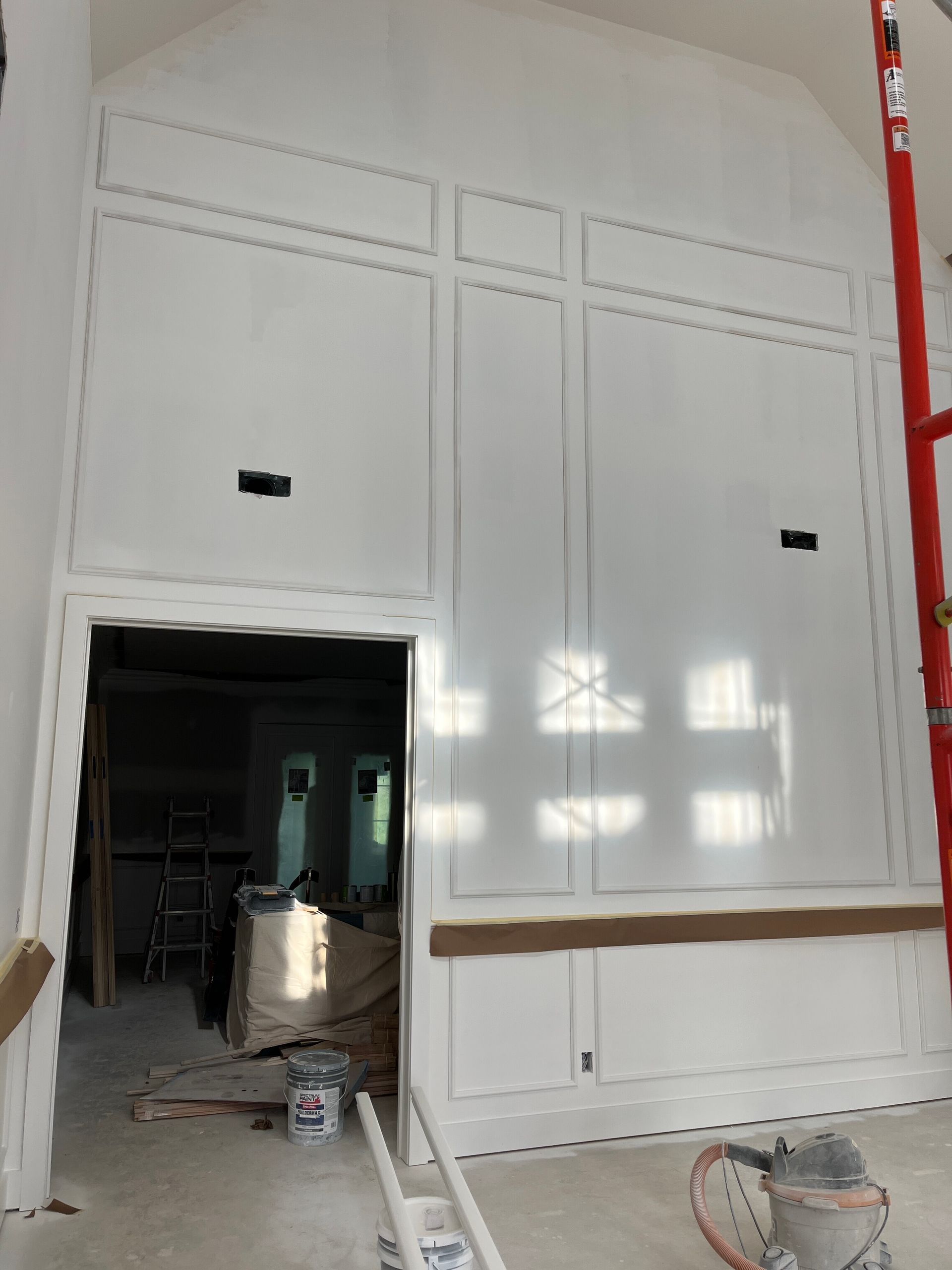 A large white wall with a red scaffolding in front of it