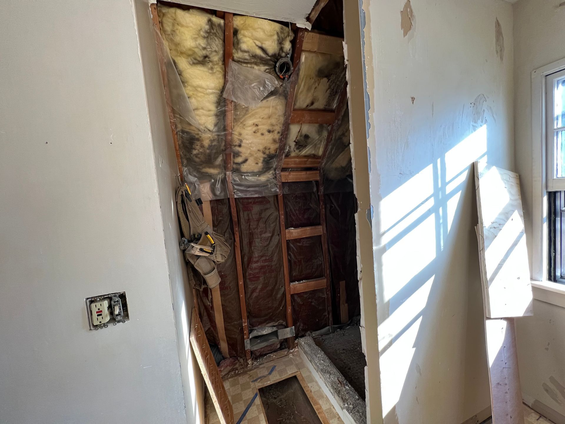 A room with a hole in the wall and a ladder in it.